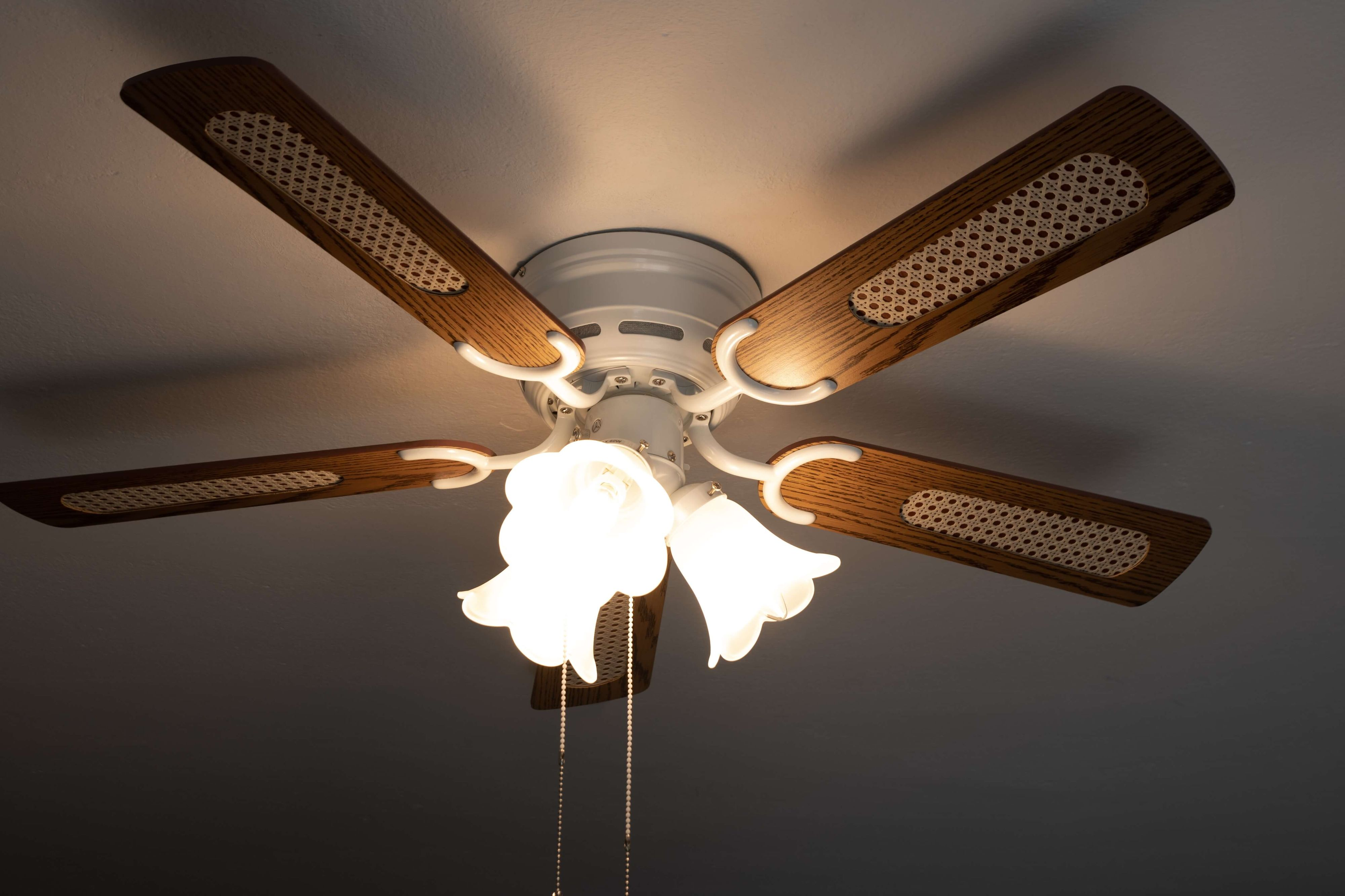 Ein Deckenventilator mit Holzflügeln und Lichtern.