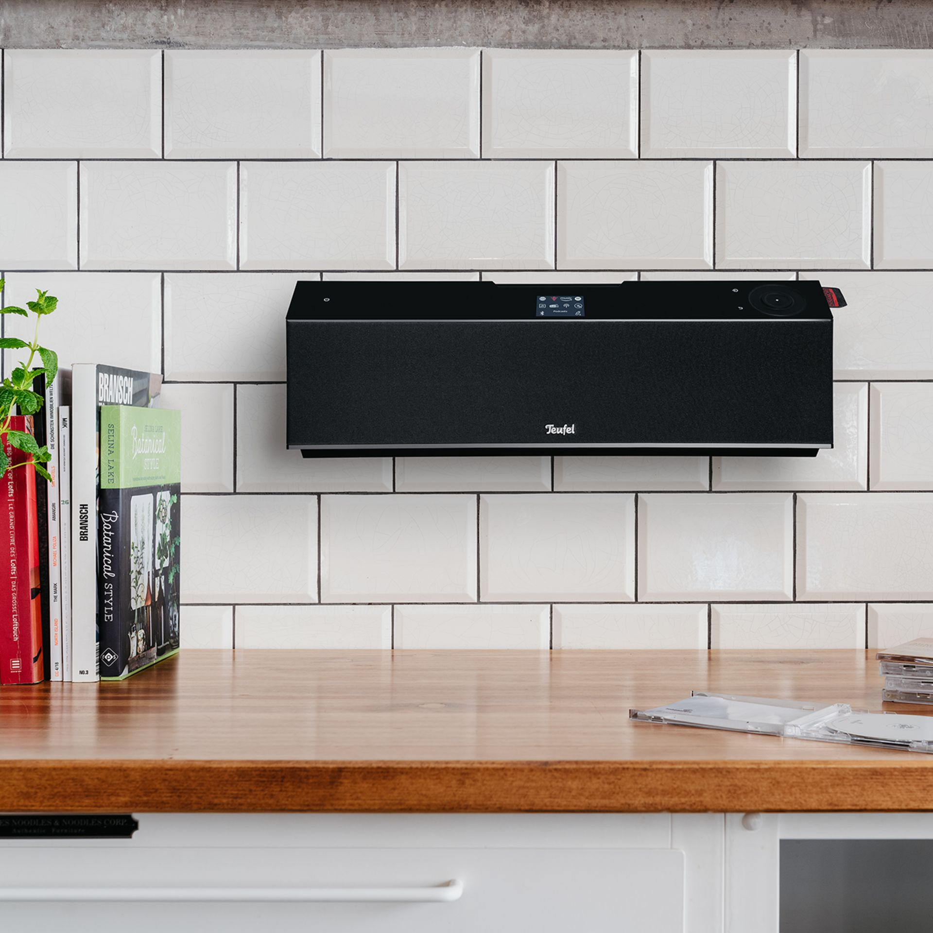 A black speaker mounted on white tiled wall.