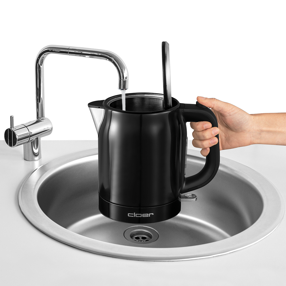 Bollitore nero riempito con acqua dal rubinetto. In un lavandino. Marchio Cloer visibile. Manico e base neri.