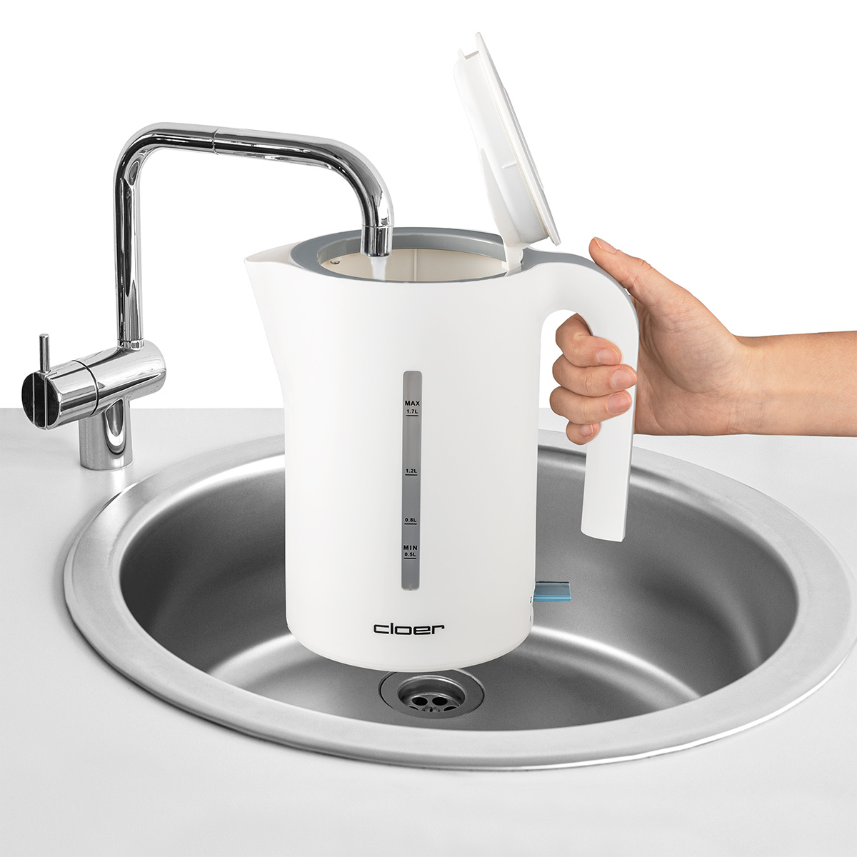 Weißer Wasserkocher in einem Waschbecken, Deckel geöffnet und Hand hält ihn.