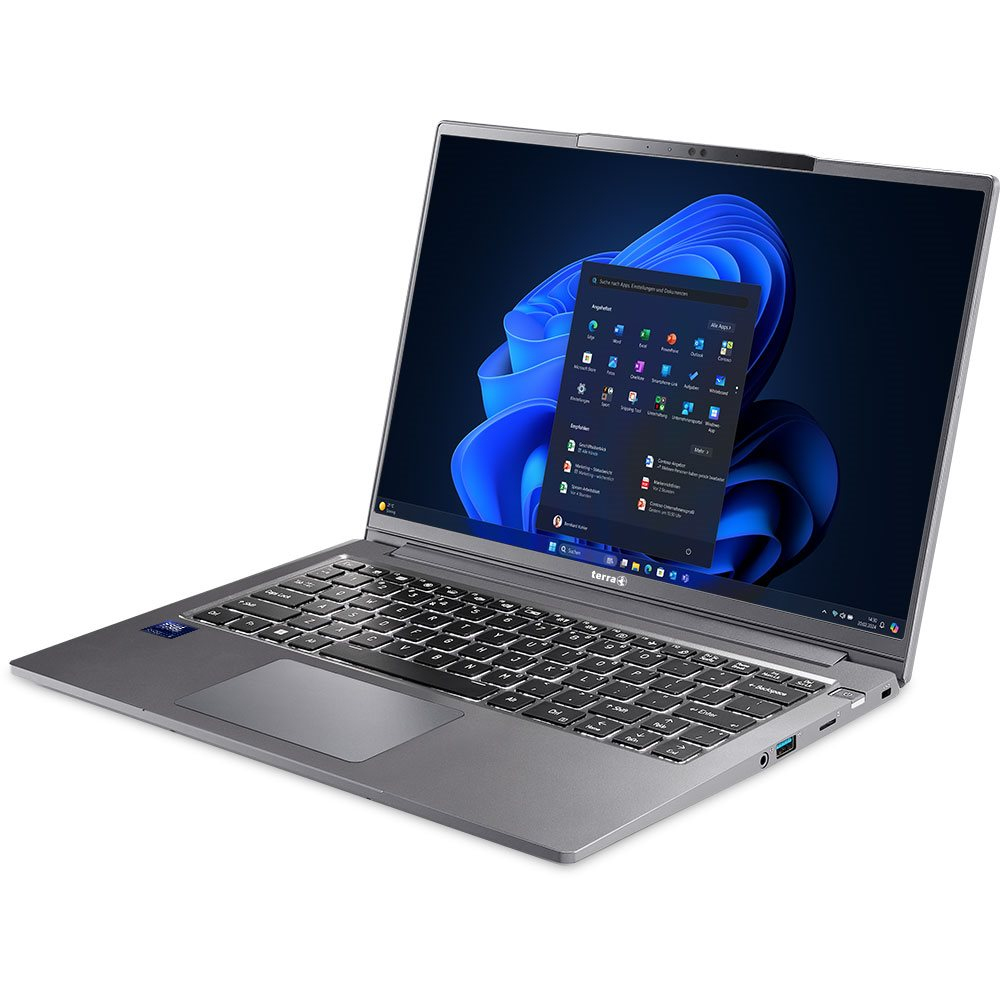 Szary laptop z ciemnym ekranem pokazującym pulpit systemu Windows, umieszczony na białej powierzchni.