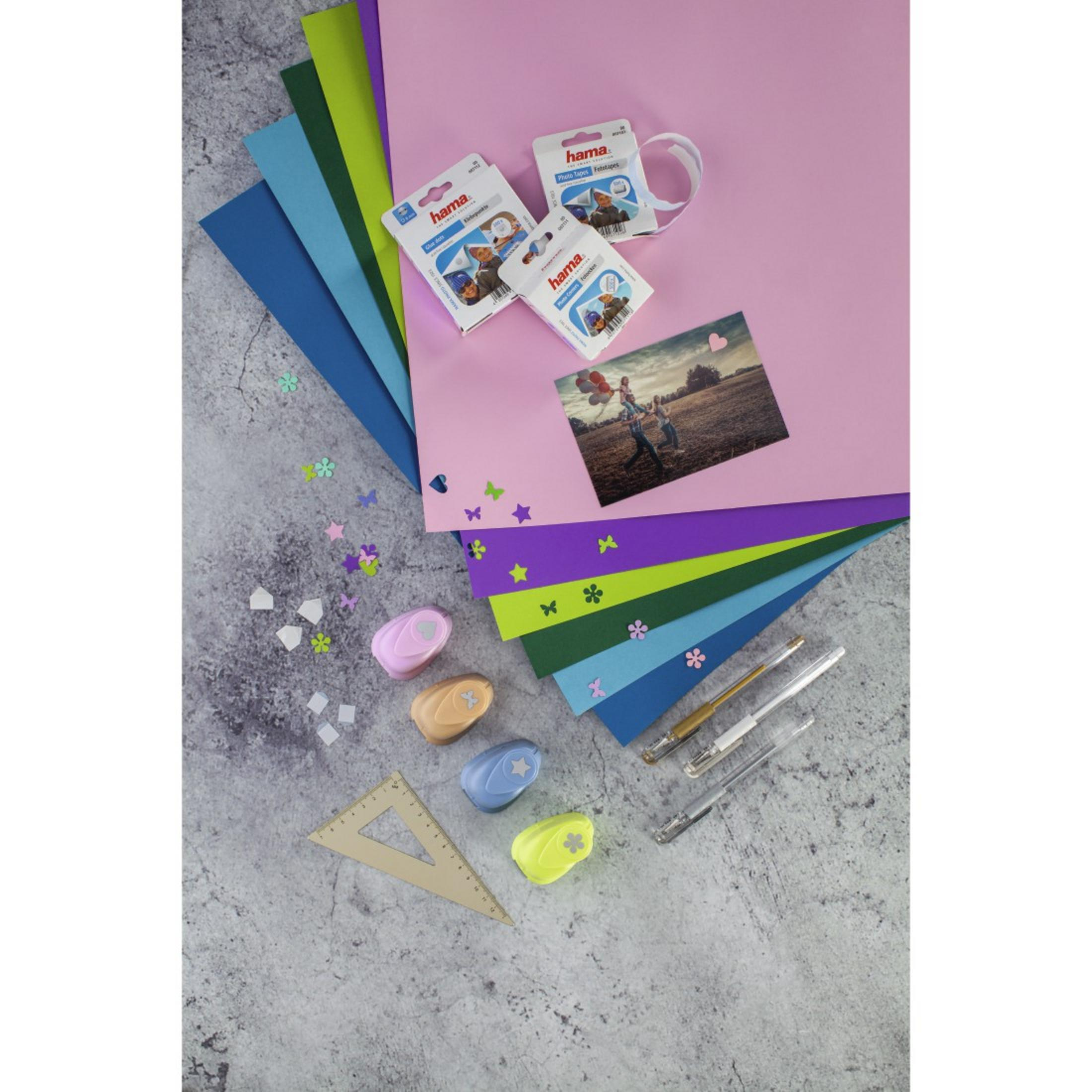 Układ płaski z materiałami do rękodzieła: kolorowy papier, dziurkacze, długopisy, taśmy fotograficzne.