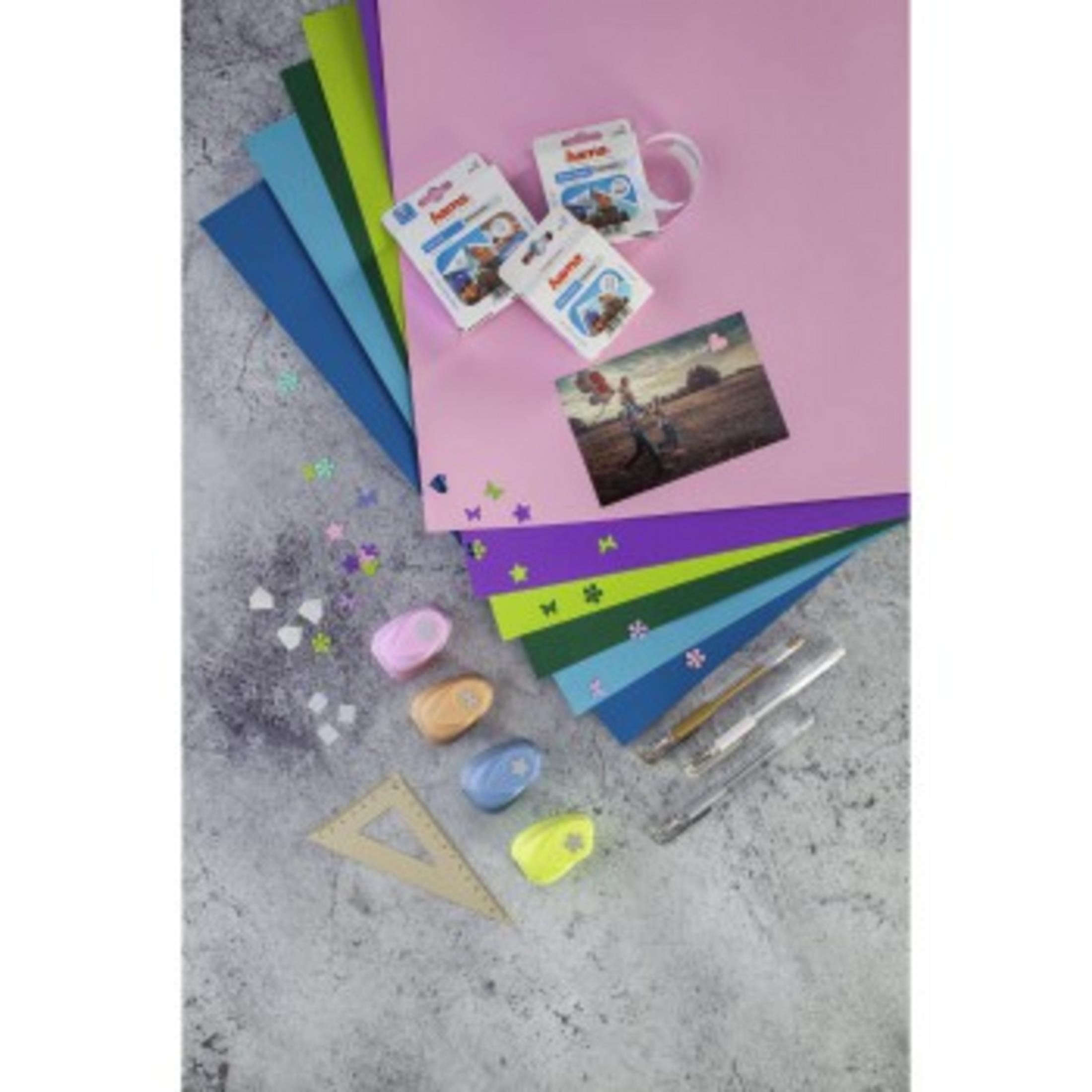 Widok z góry na materiały do rękodzieła: kolorowy papier, dziurkacze, długopisy, taśmy fotograficzne.