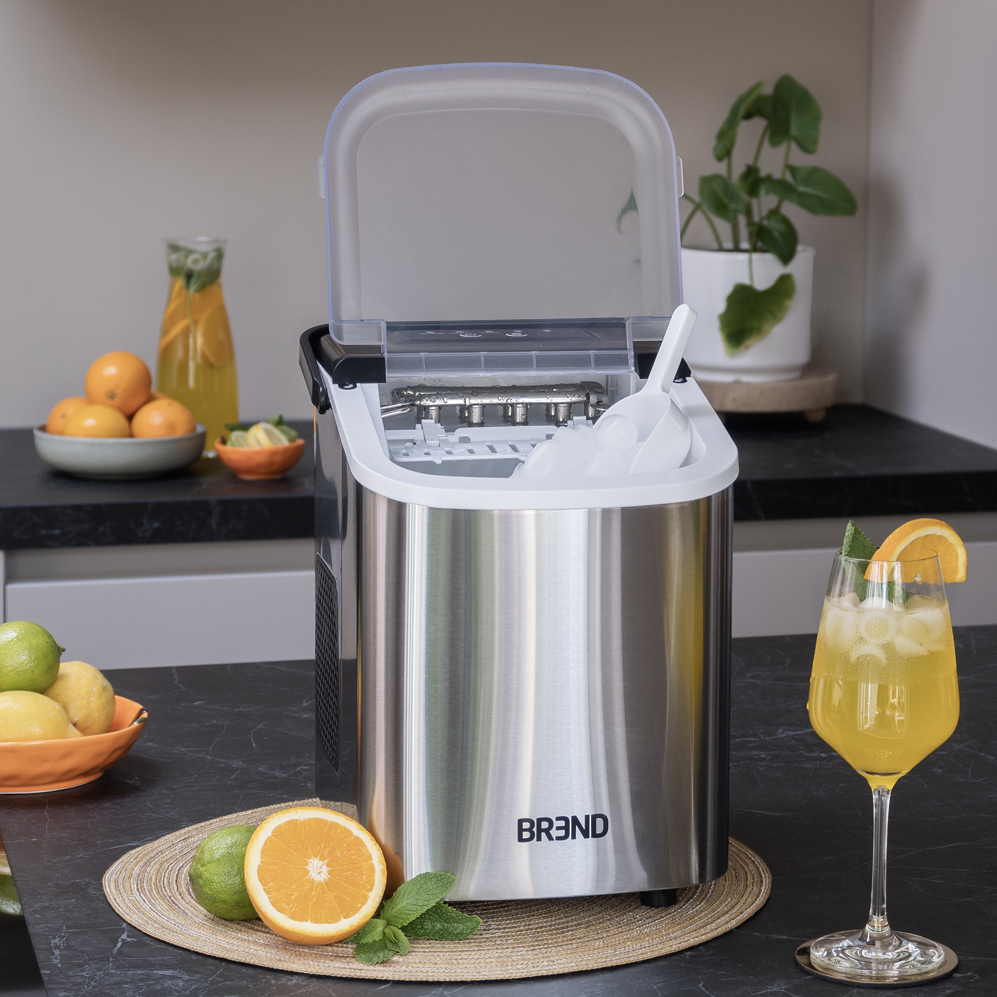 Stainless steel ice maker with lid open. A cocktail is on the side.