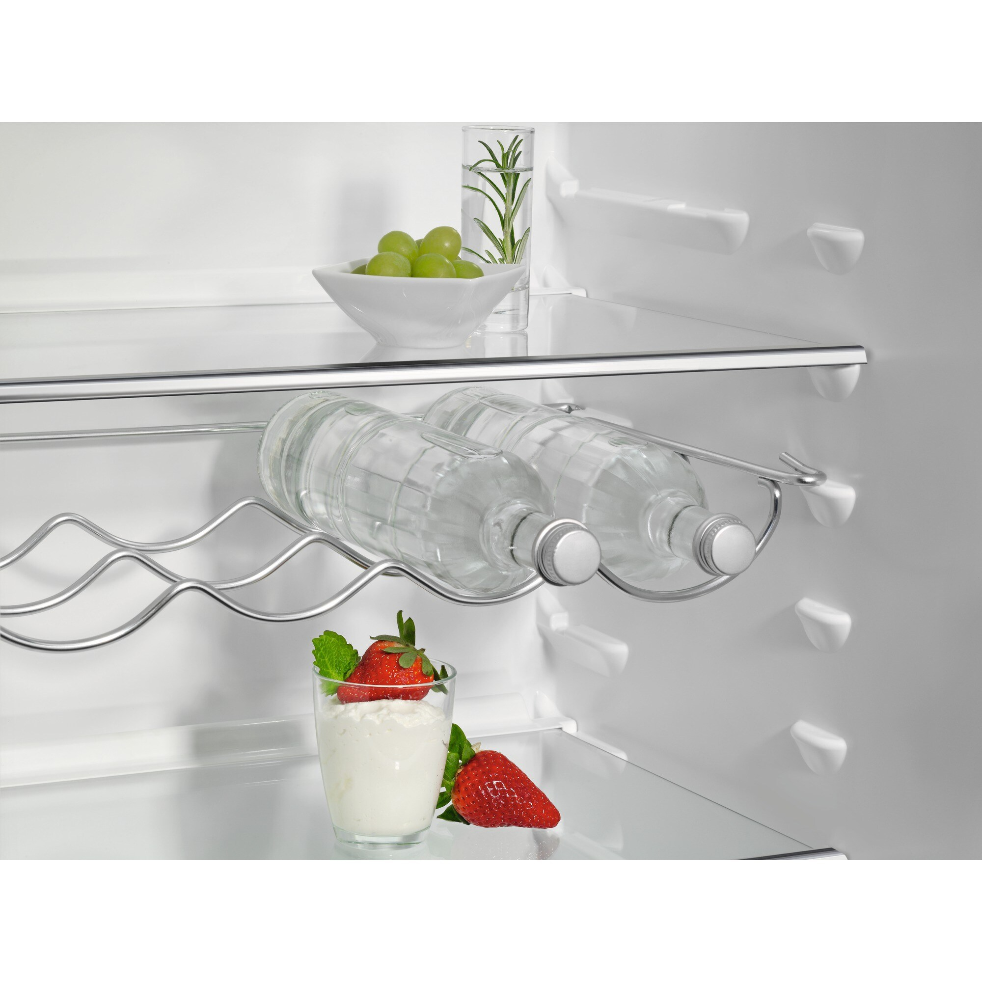 Dentro de la nevera: botellas de agua, uvas, fresas y un vaso con yogur.