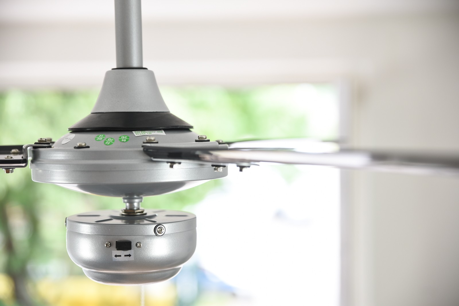 Ventilatore a soffitto con alloggiamento motore e pale argentate.
