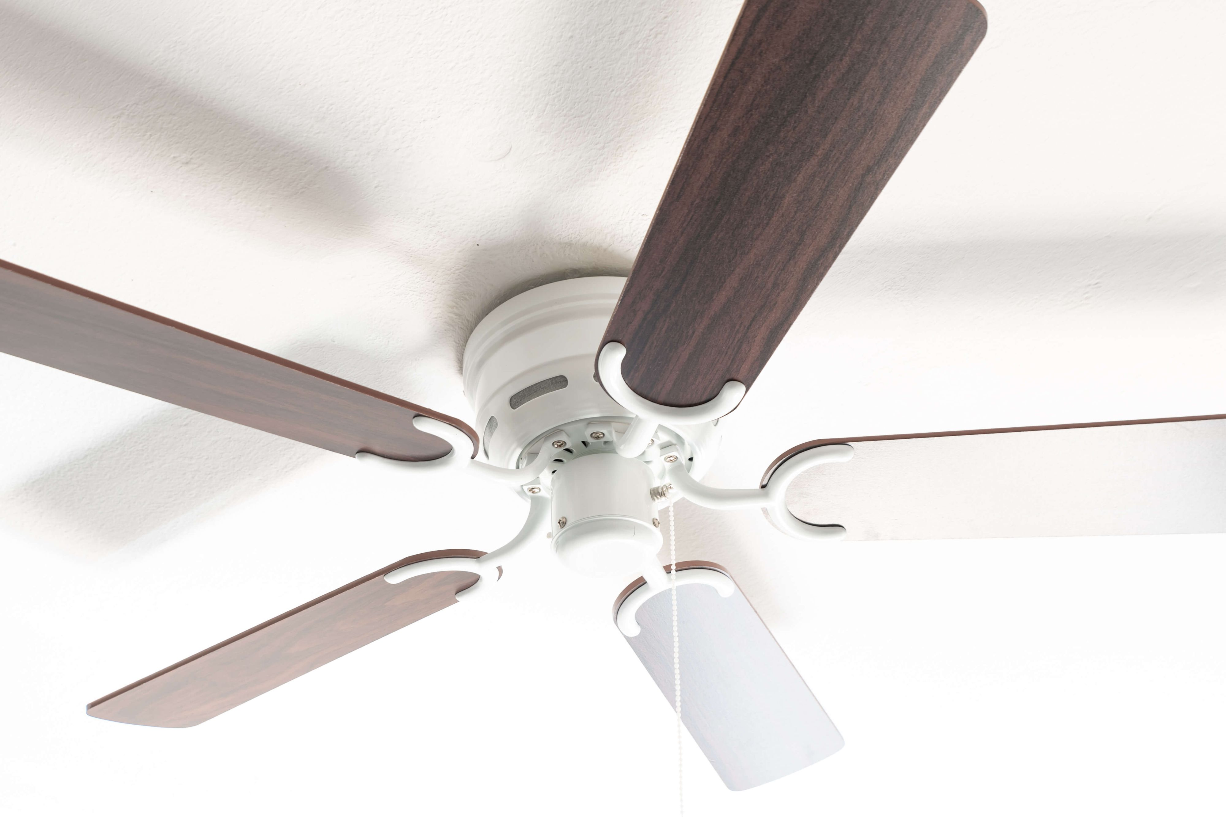 Deckenventilator mit braunen Flügeln und weißem Gehäuse. Weißer Hintergrund.