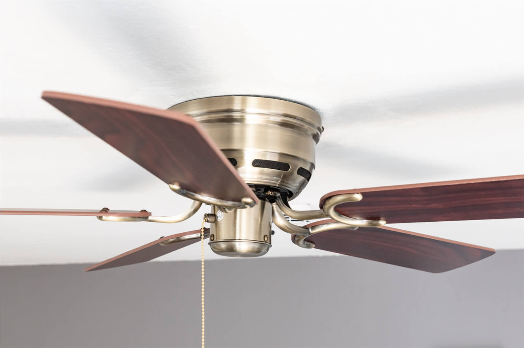 Ein Deckenventilator mit dunklen Holzblättern und einem Messing-Motorgehäuse.