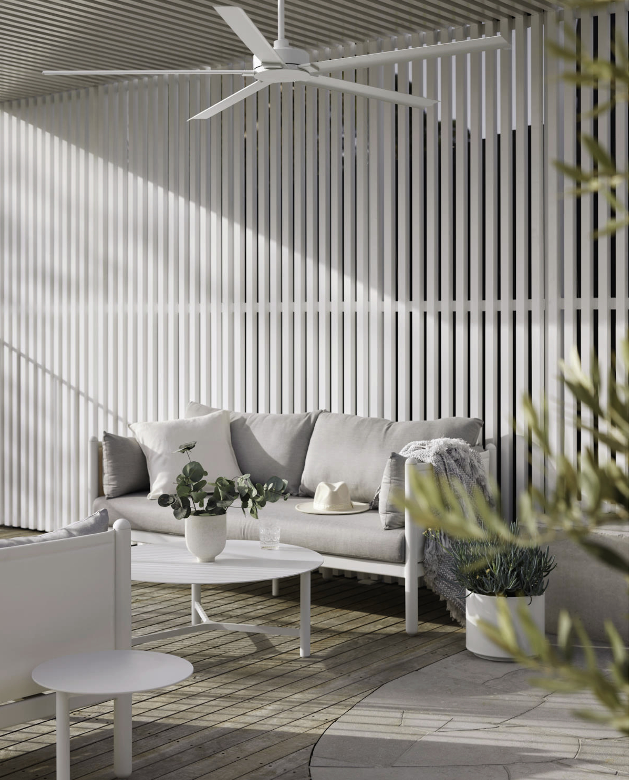 Terrasse im Freien mit Sofa, Tisch und Pflanzen, die eine entspannte Umgebung schaffen.