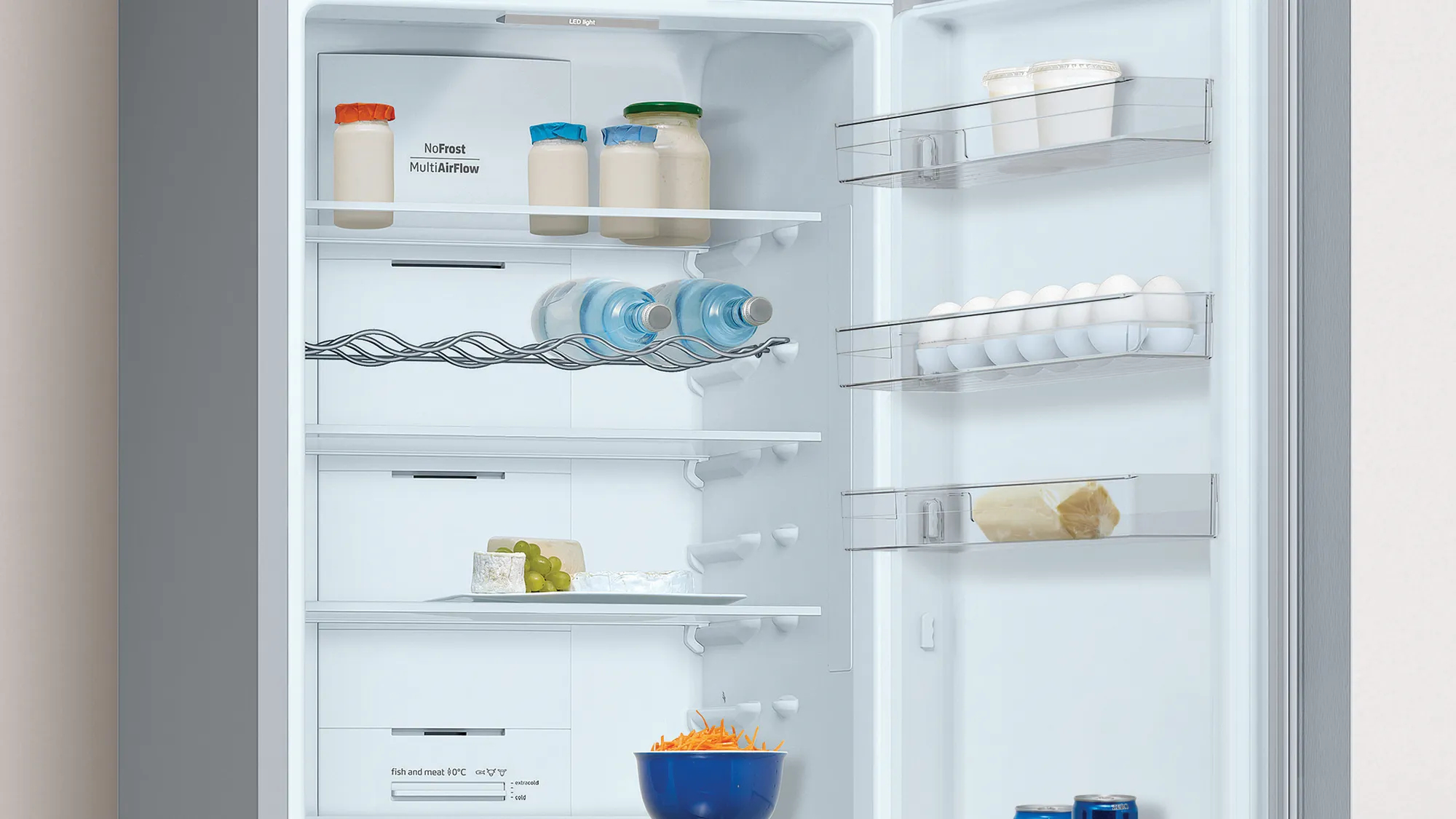 Interior de refrigerador abierto. Estantes con alimentos, incluyendo frascos, botellas, queso y huevos.