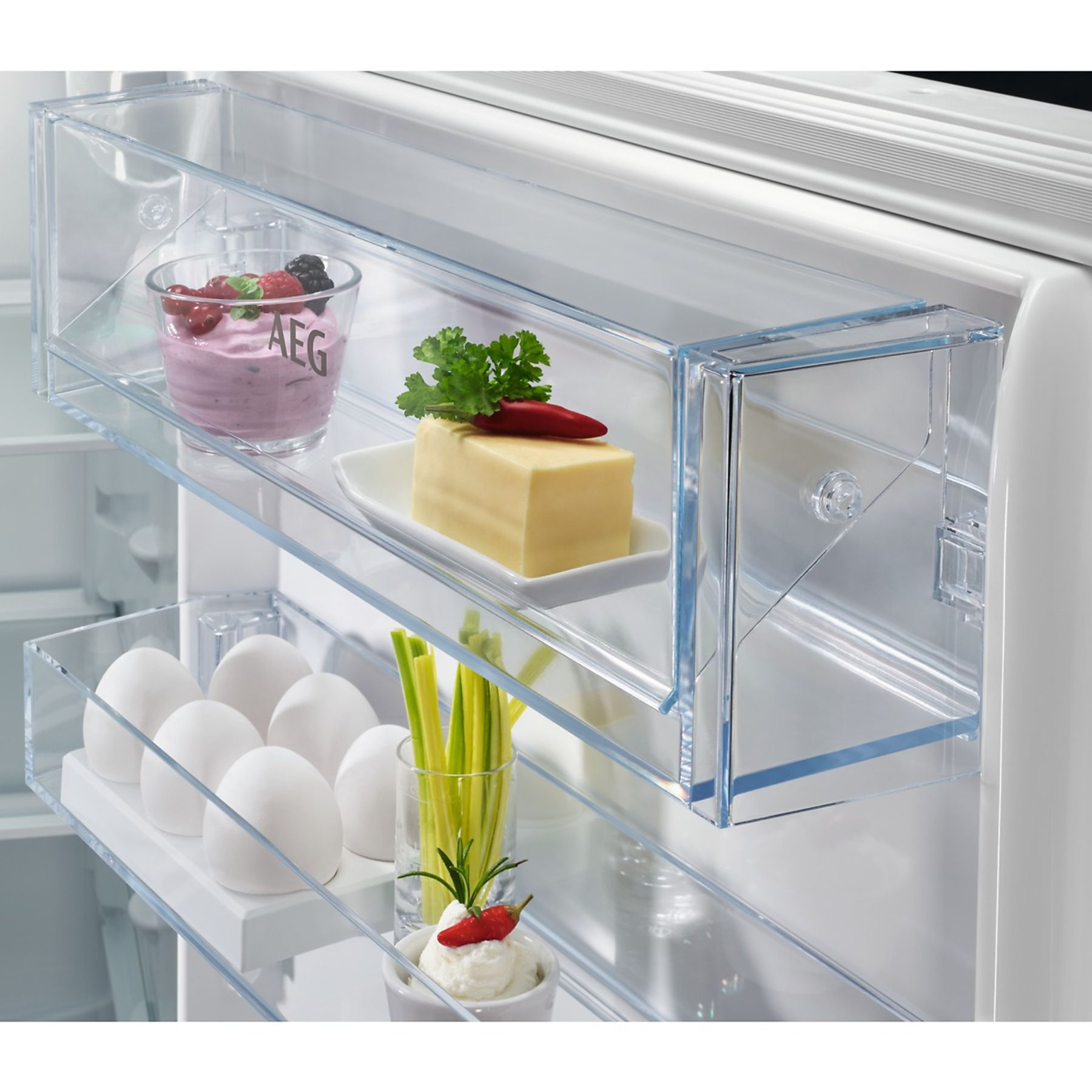 Interieur van koelkast met glazen planken met etenswaren als eieren, kaas en yoghurt.
