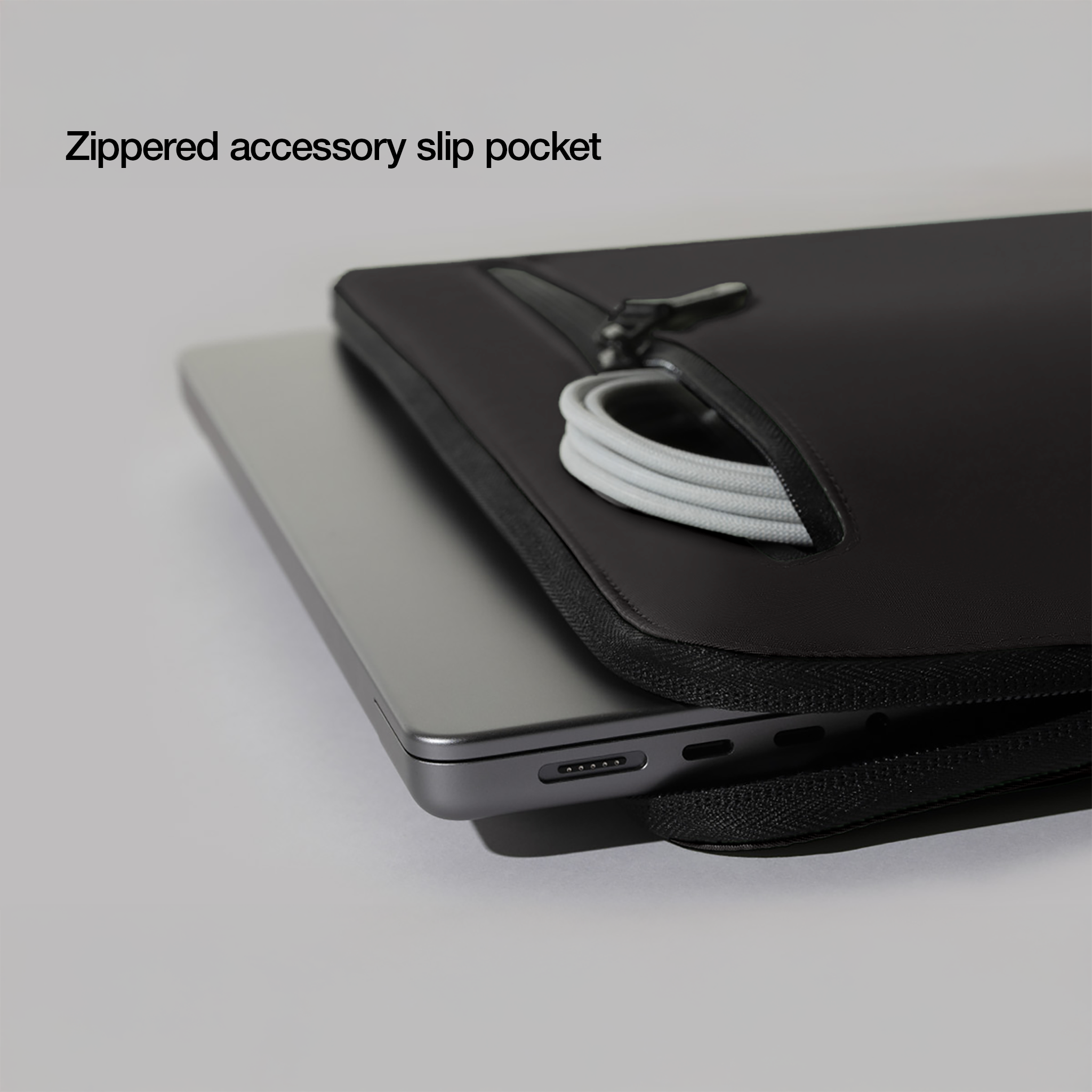 Laptop in una custodia nera. La custodia ha una cerniera e una tasca. È visibile un cavo bianco.