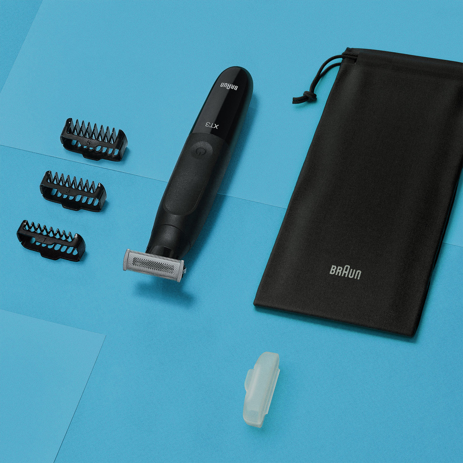 Schwarzer Trimmer mit Aufsätzen und einem schwarzen Beutel auf blauer Oberfläche.