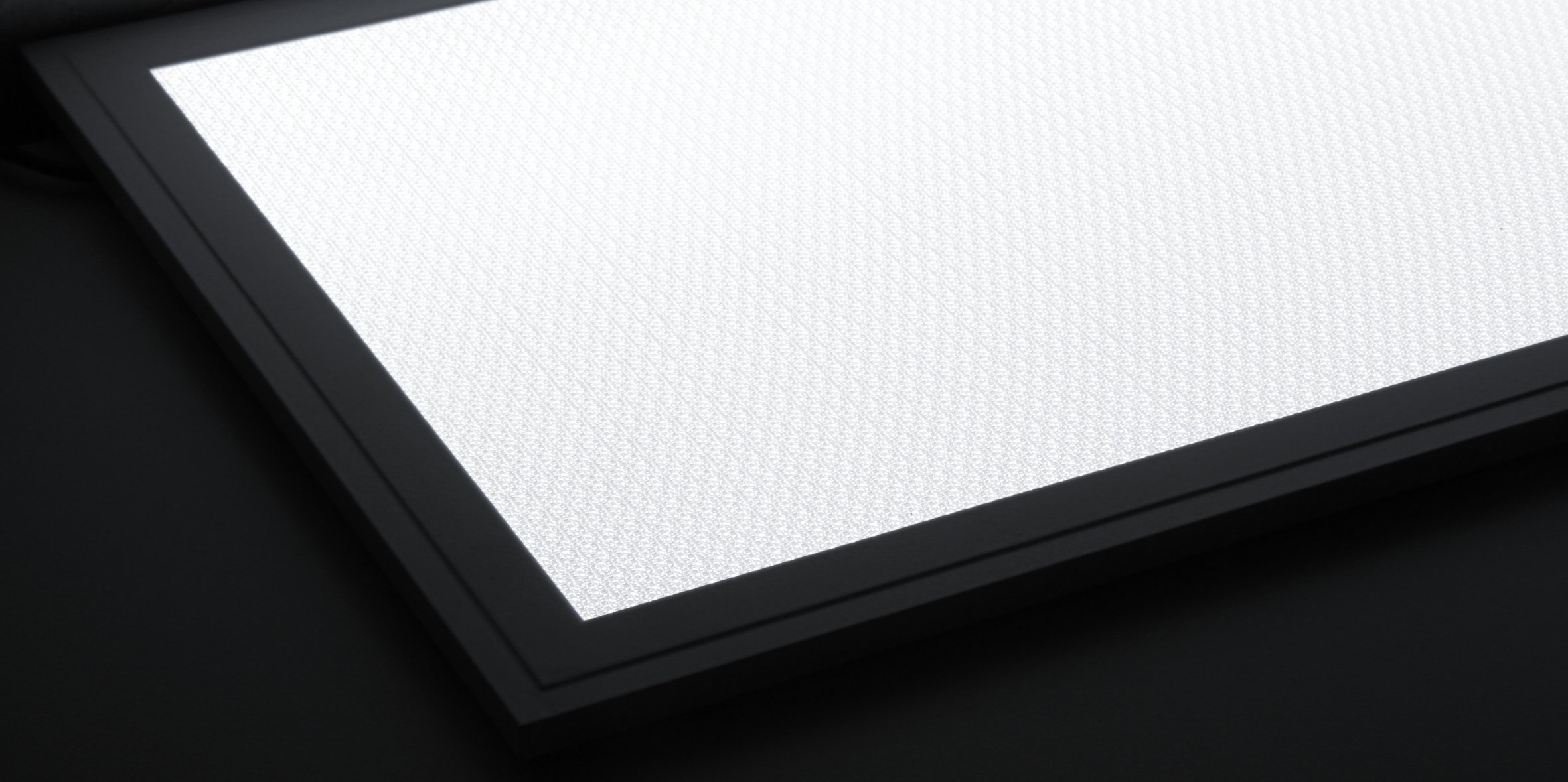 Ein helles weißes Lichtpanel mit schwarzem Rahmen vor dunklem Hintergrund, schräge Ansicht.