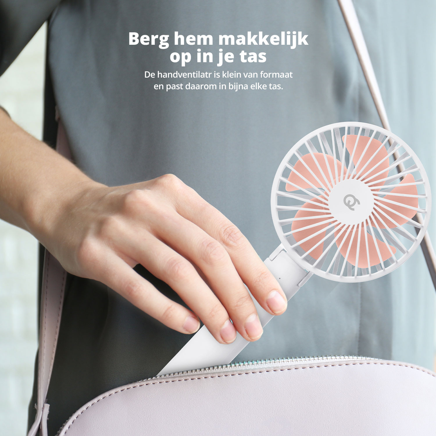 Hand einer Frau, die einen weiß-rosa Ventilator in eine hellviolette Handtasche legt.