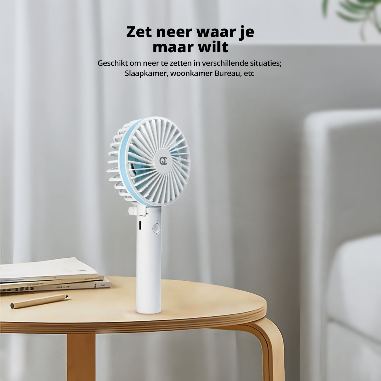 Portable fan on a table, near a notebook and a pencil.