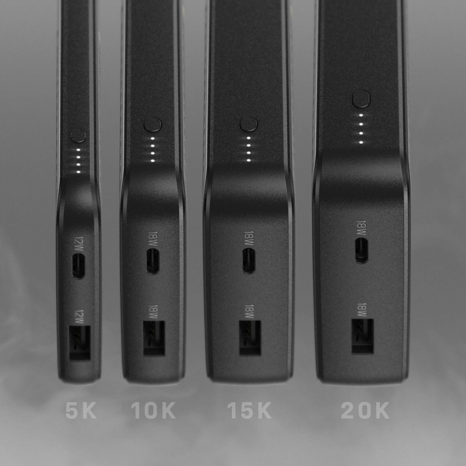 Quattro power bank neri con porte di ricarica e indicatori di alimentazione sono allineati.