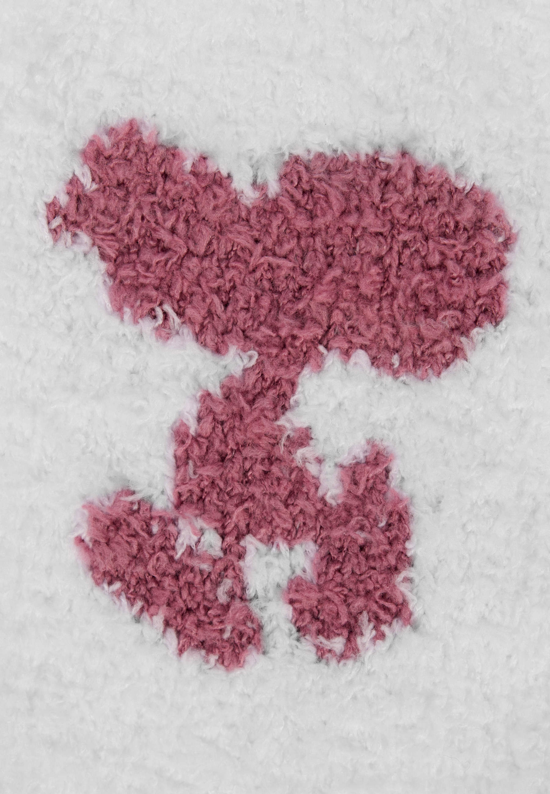 Weißer Teppich mit rosa, flauschiger, unregelmäßiger Form. Der Teppich ist flauschig, der Hintergrund weiß.