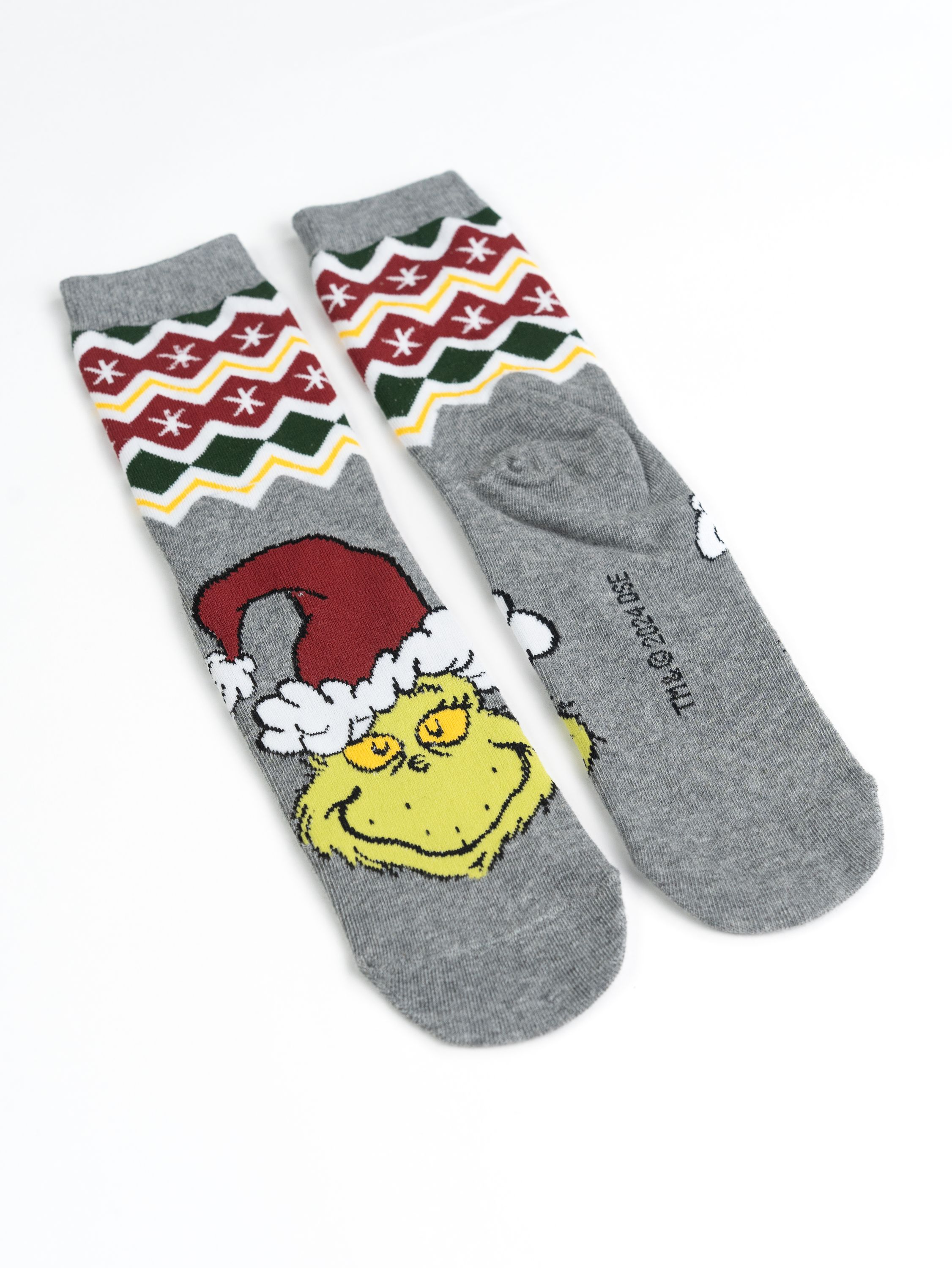 Zwei graue Socken mit Grinch-Design. Eine Socke zeigt Grinchs Gesicht, die andere ein Muster.