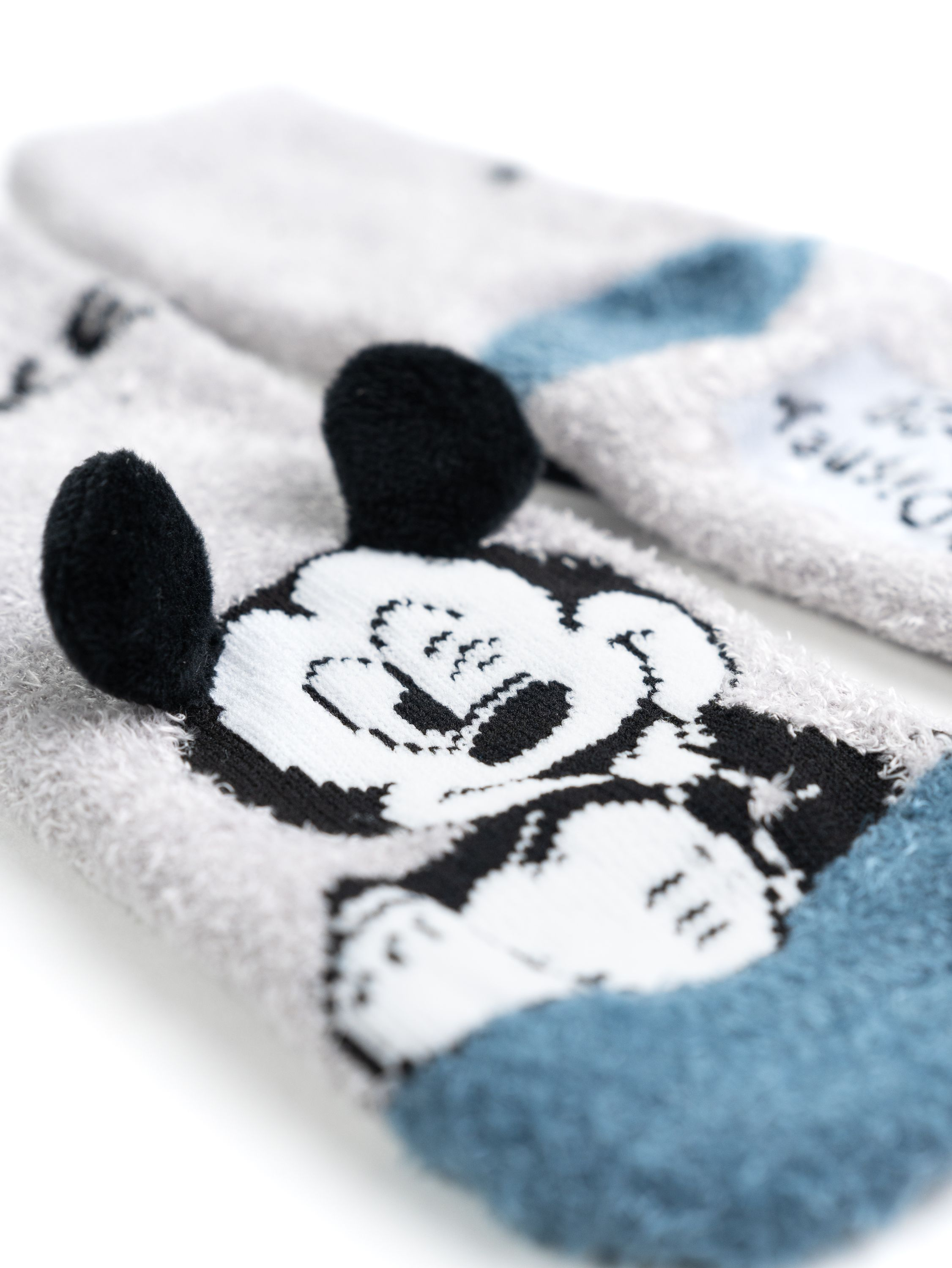 Nahaufnahme von drei Socken mit Mickey Mouse Gesicht, Ohren und blauem Bündchen-Design.
