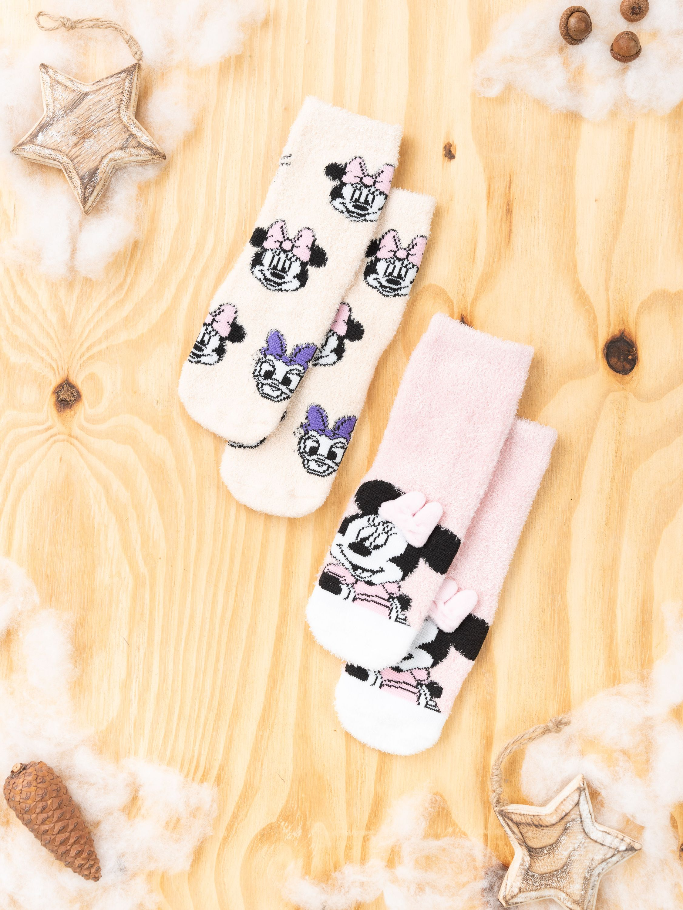 Zwei Paar Socken: eine rosa mit Minnie, eine cremefarbene mit Daisy, beide mit Blumenmustern und Schleifen.