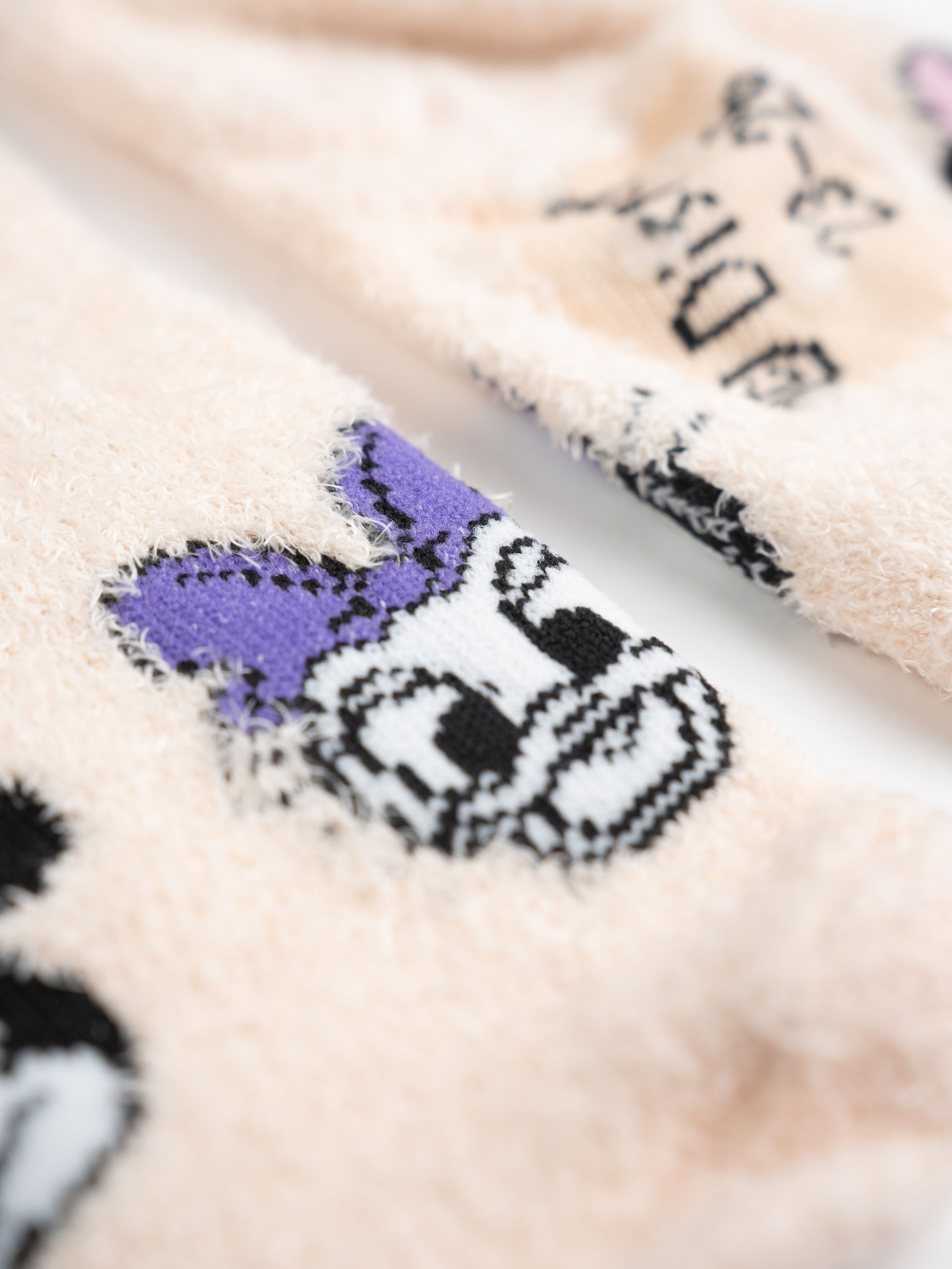 Nahaufnahme von zwei flauschigen Socken mit einem Cartoon-Gesicht.