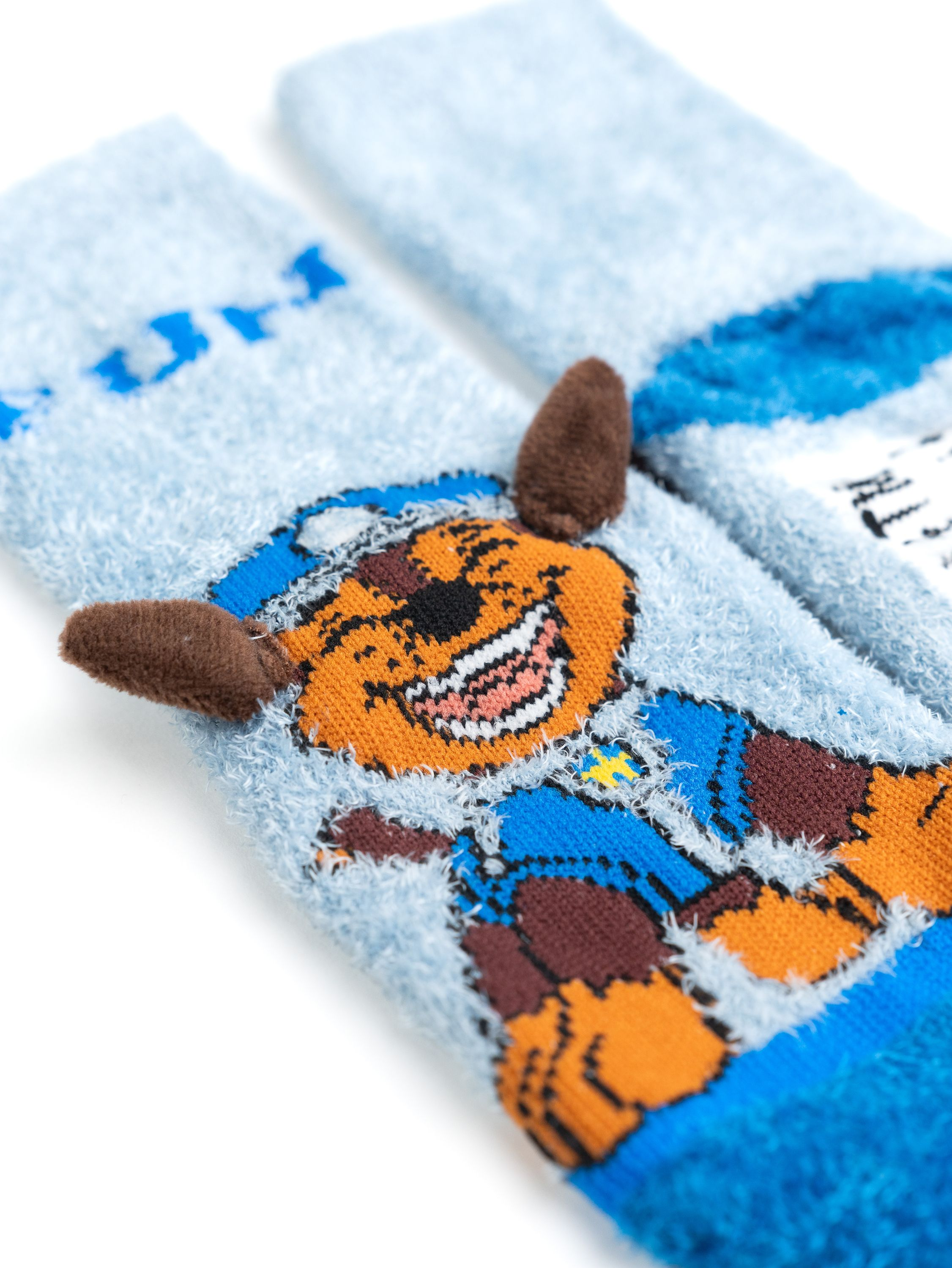 Nahaufnahme von zwei hellblauen Socken mit dem Gesicht einer Zeichentrickfigur.