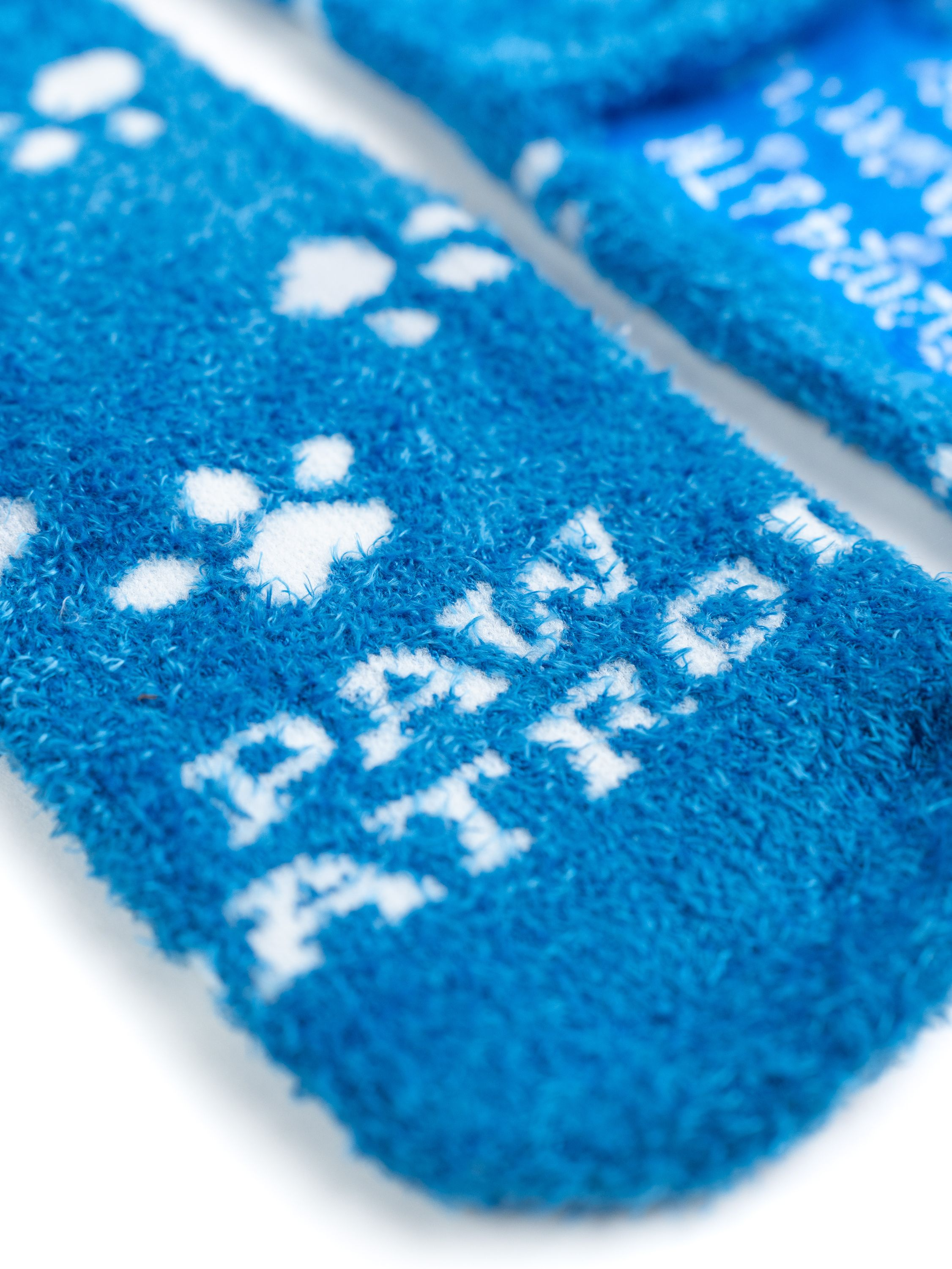 Nahaufnahme von blauen Socken mit weißen Pfotenabdrücken und dem Text 'PAW PATROL'.