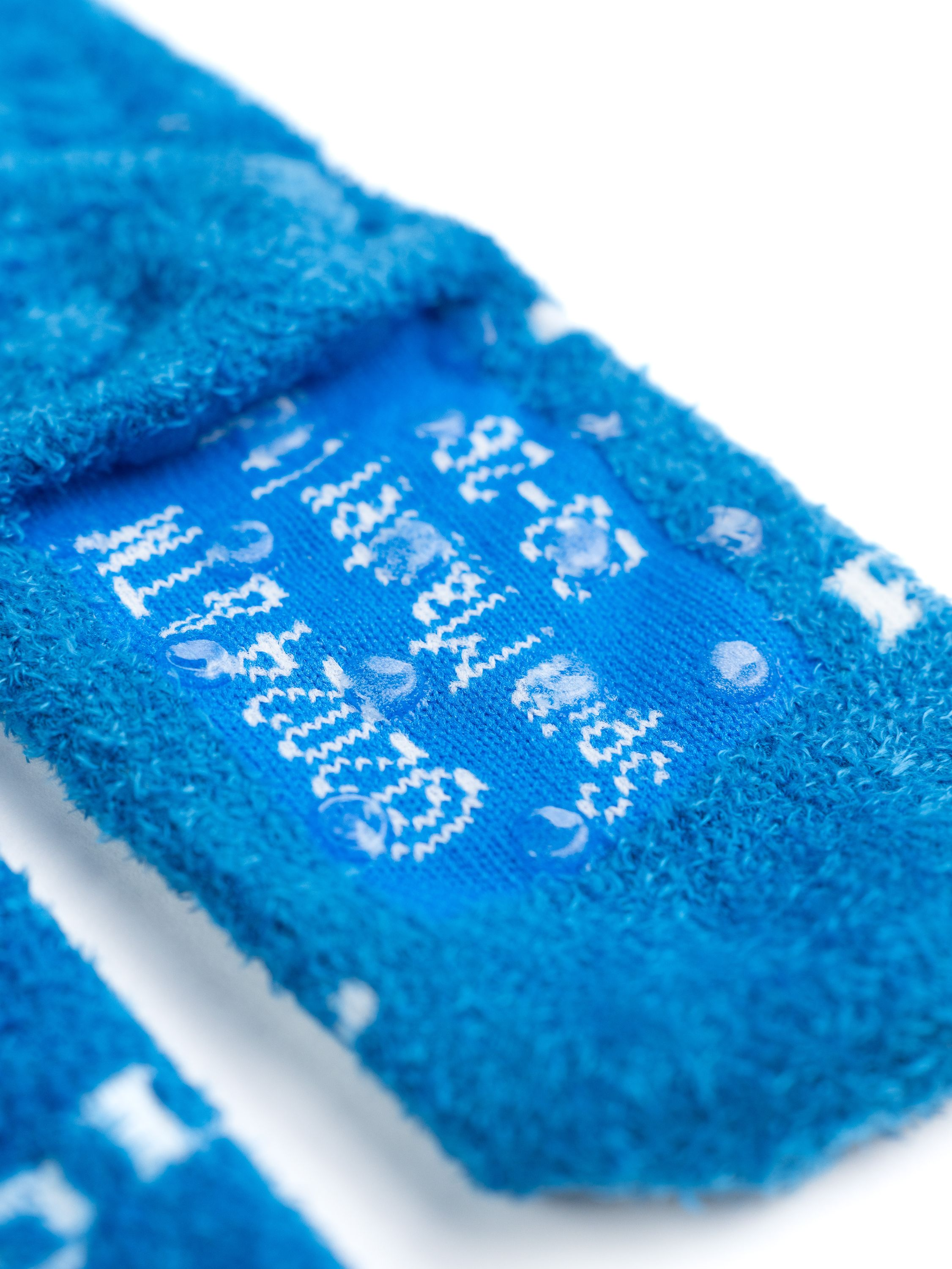 Nahaufnahme von blauen Socken mit weißen Mustern und Wassertropfen. Text auf den Socken sichtbar.