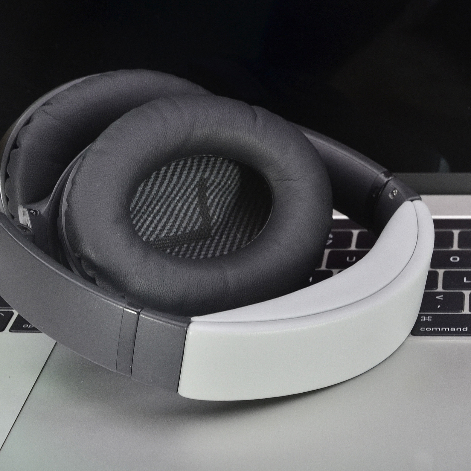 Cuffie over-ear grigie e nere, appoggiate su un laptop.