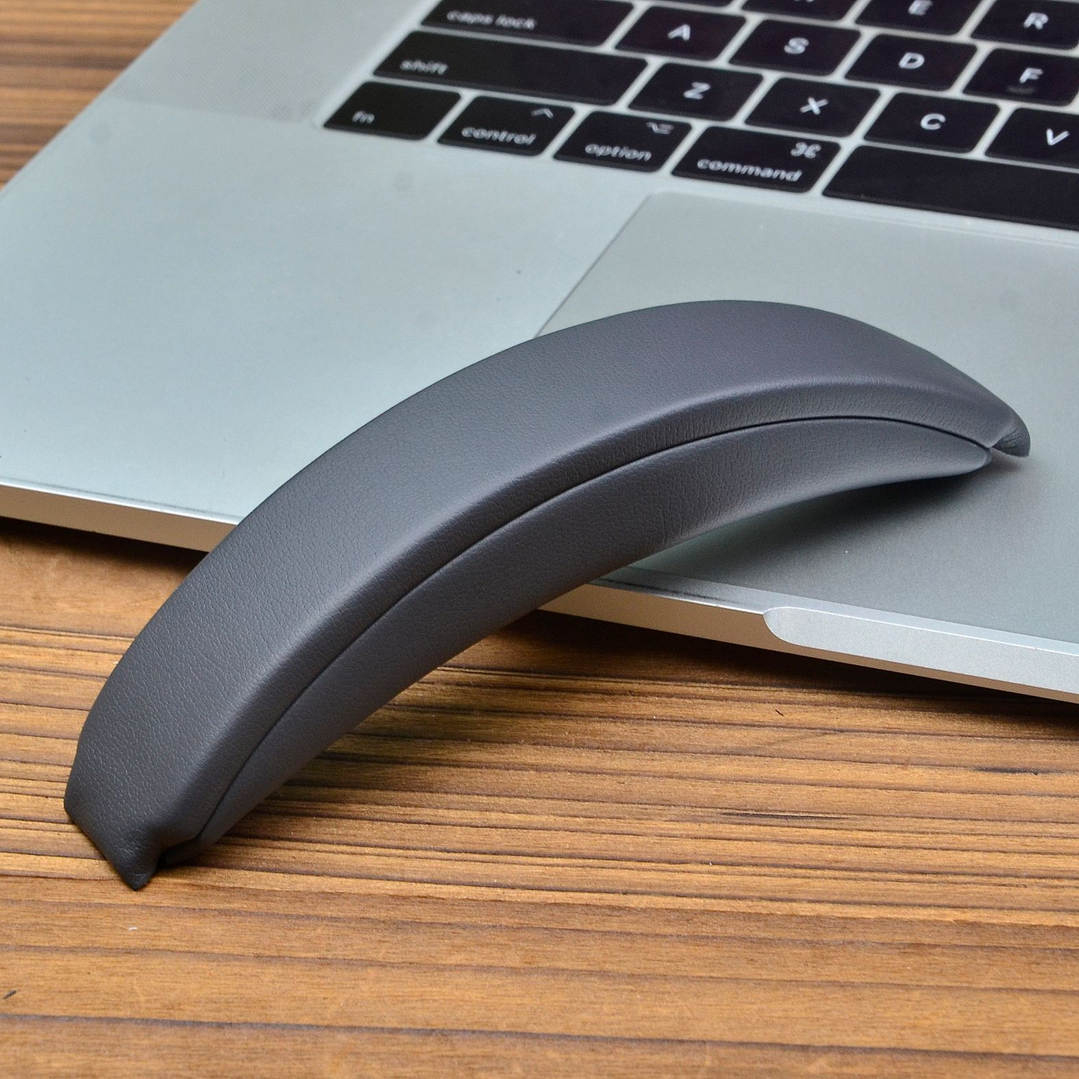 Un poggiapolsi grigio è su una tastiera di un laptop. Lo sfondo è un tavolo di legno.