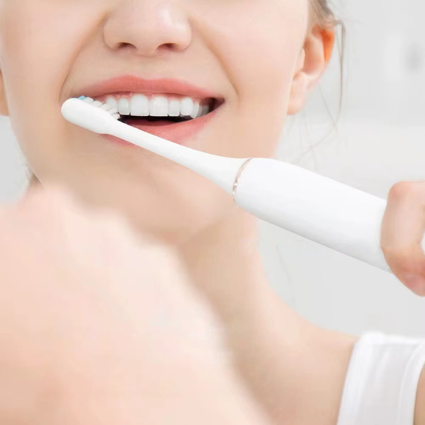 Kobieta myjąca zęby szczoteczką elektryczną. Zbliżenie na jej usta i szczoteczkę.