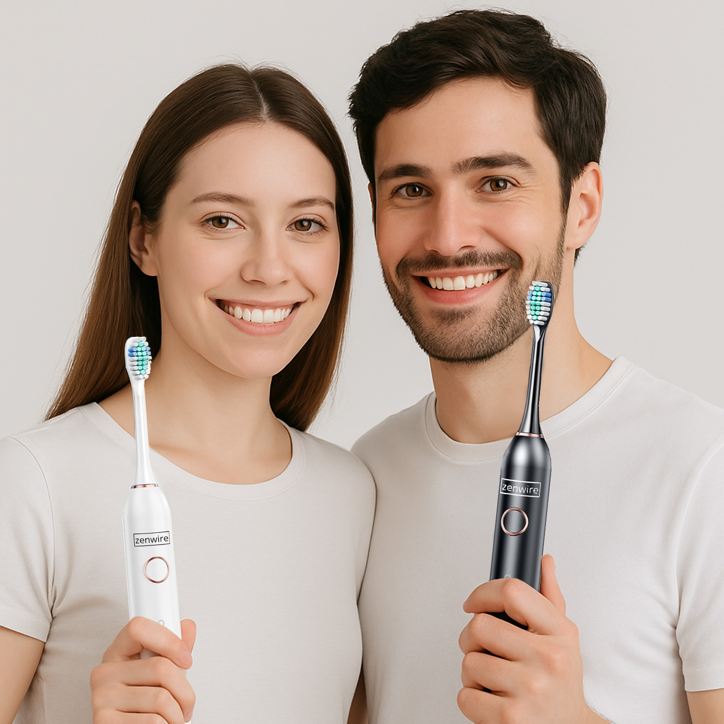 Para trzymająca elektryczne szczoteczki do zębów, jedna biała, jedna czarna, uśmiechająca się do kamery.