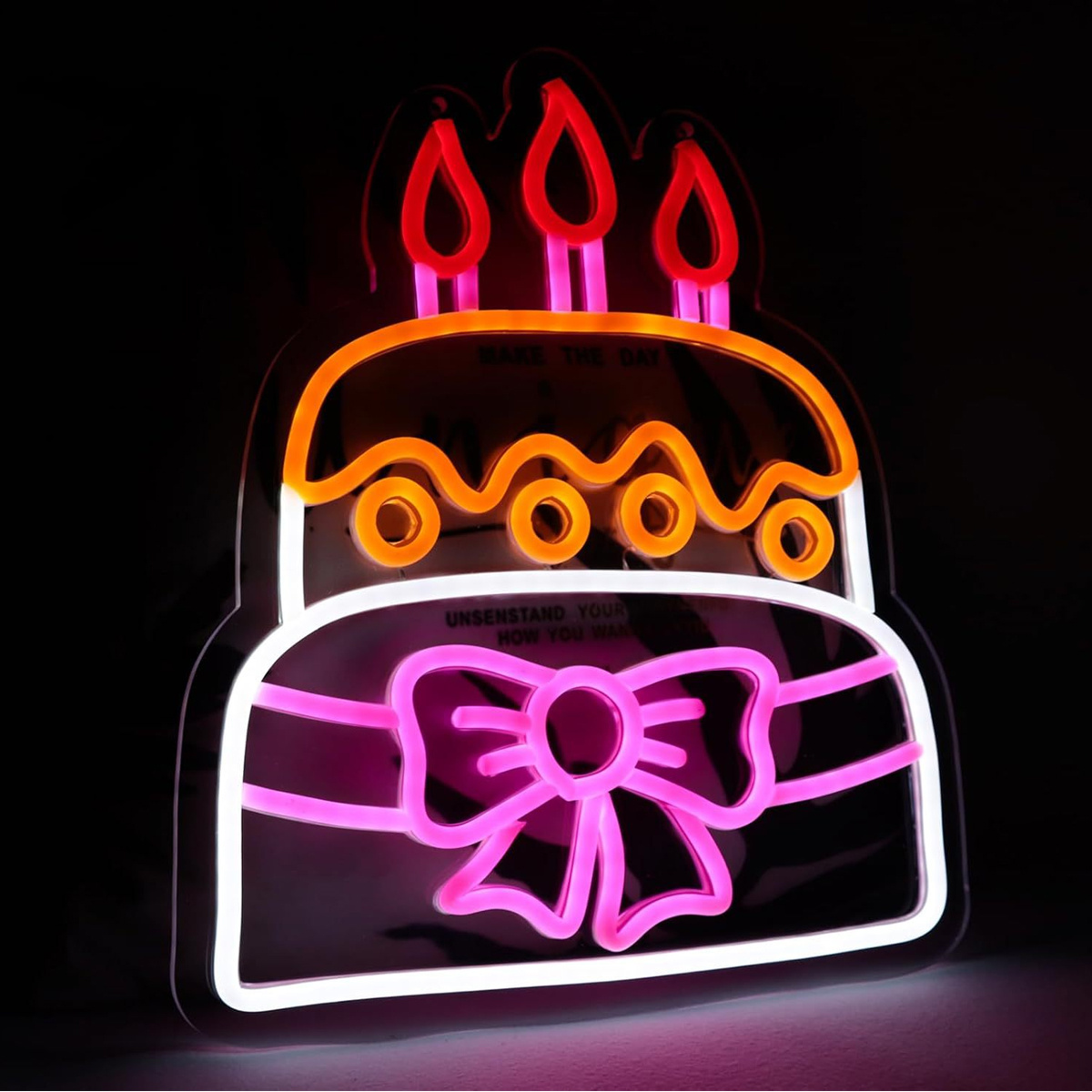 Neon-Geburtstagskuchenschild mit Kerzen, Schleife und Text auf schwarzer Oberfläche.