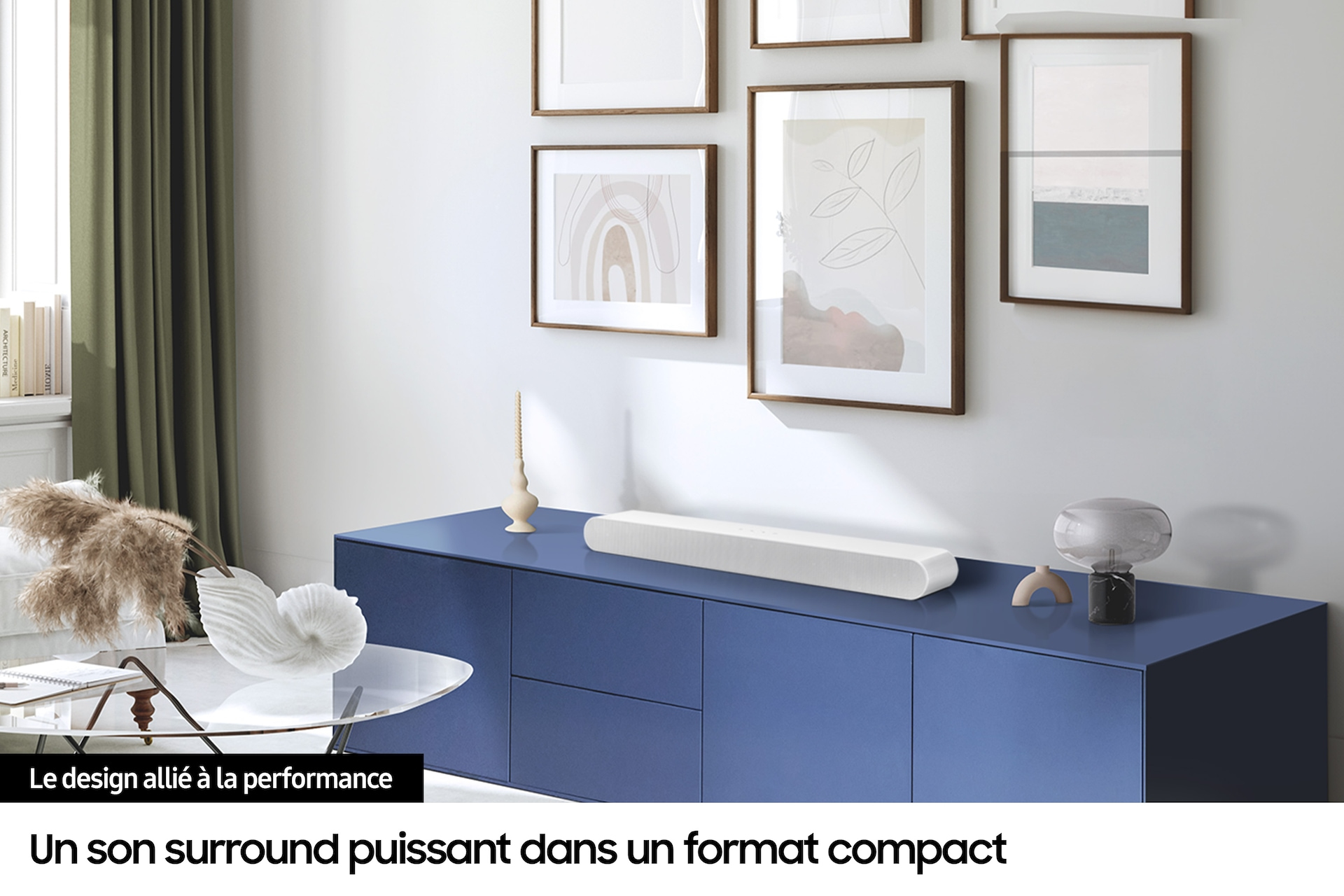 Biały soundbar na niebieskiej szafce, z oprawioną sztuką powyżej.