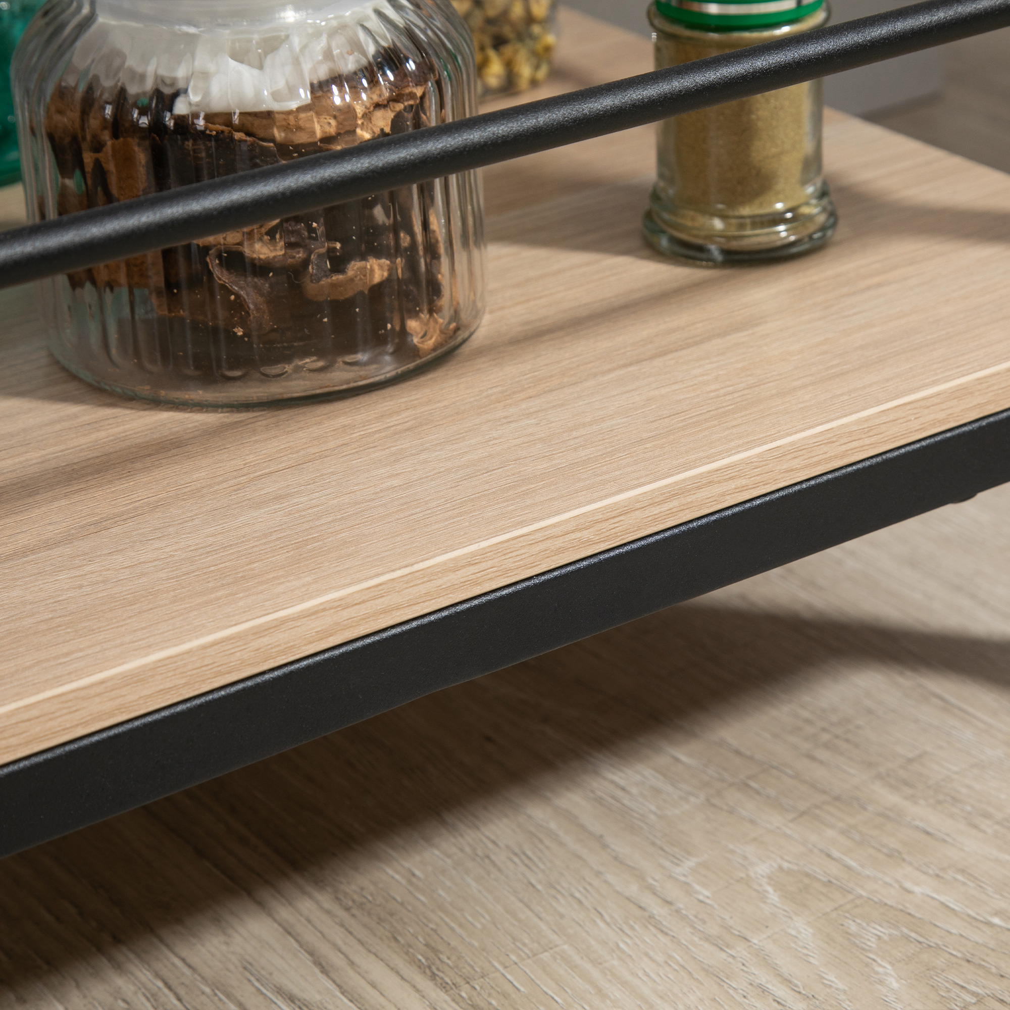 Holztisch mit Gläsern mit Keksen, Gewürzen und einem schwarzen Metallrahmen. Draufsicht.