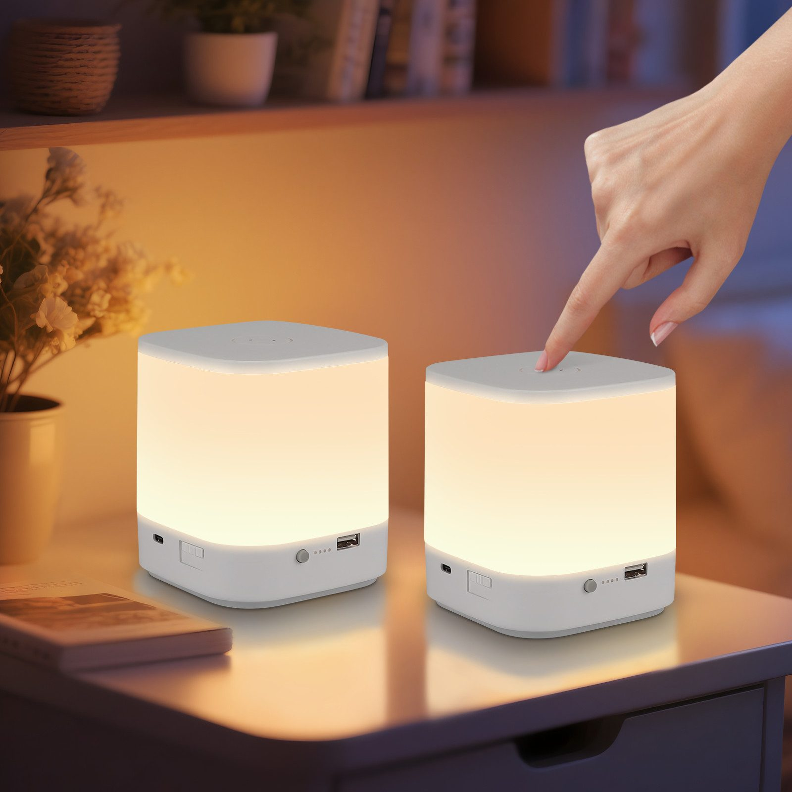 Dwie białe, dotykowe lampki nocne z możliwością ściemniania na stole. Ręka dotyka jednej lampy.
