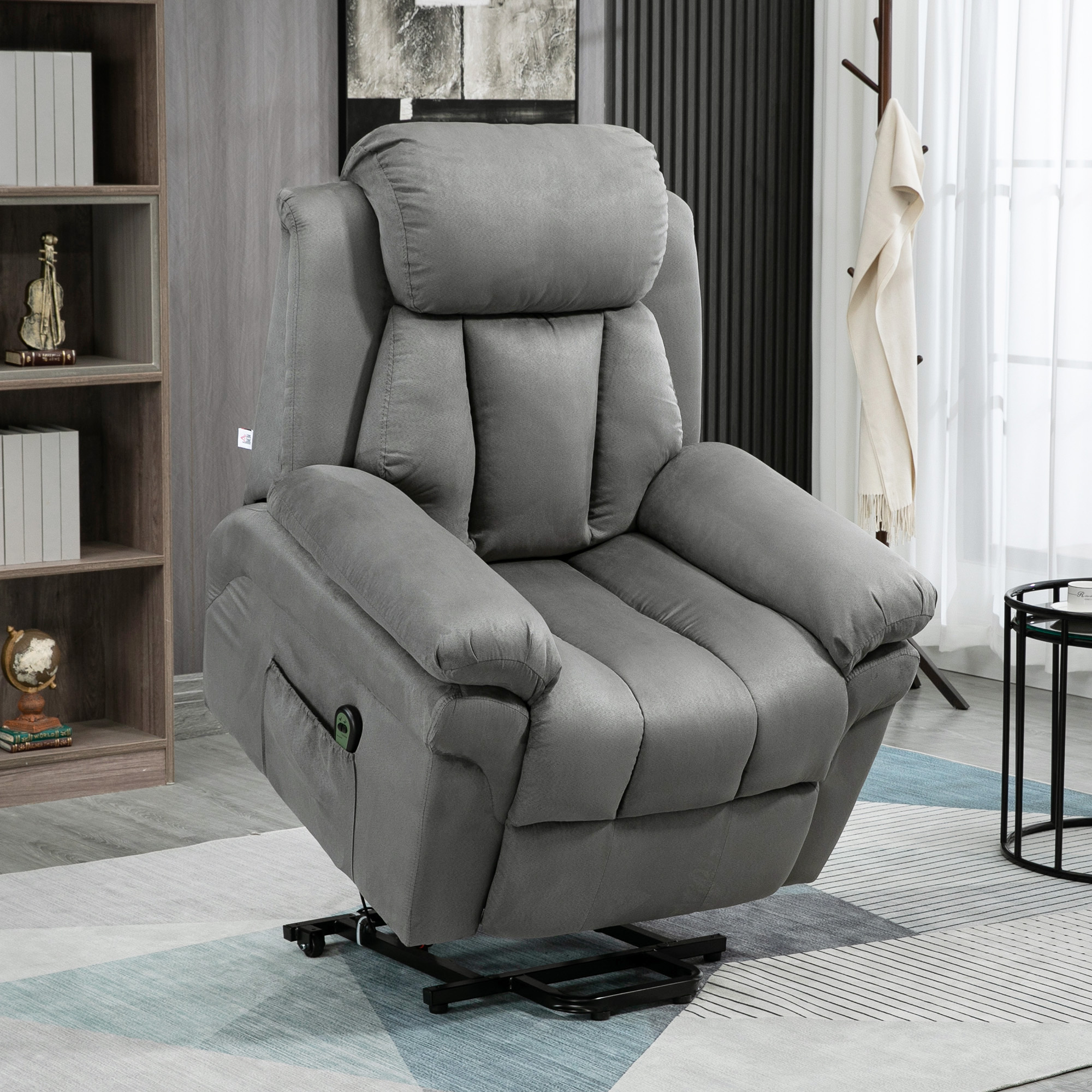 Ein grauer Relaxsessel in einer Heimumgebung, mit Bücherregal und Tisch im Hintergrund.
