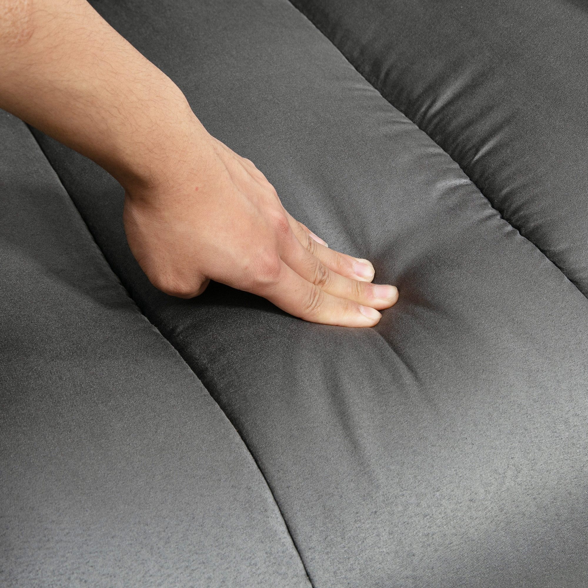 Eine Hand drückt auf die graue Oberfläche eines Relaxsessels und zeigt das weiche Material.
