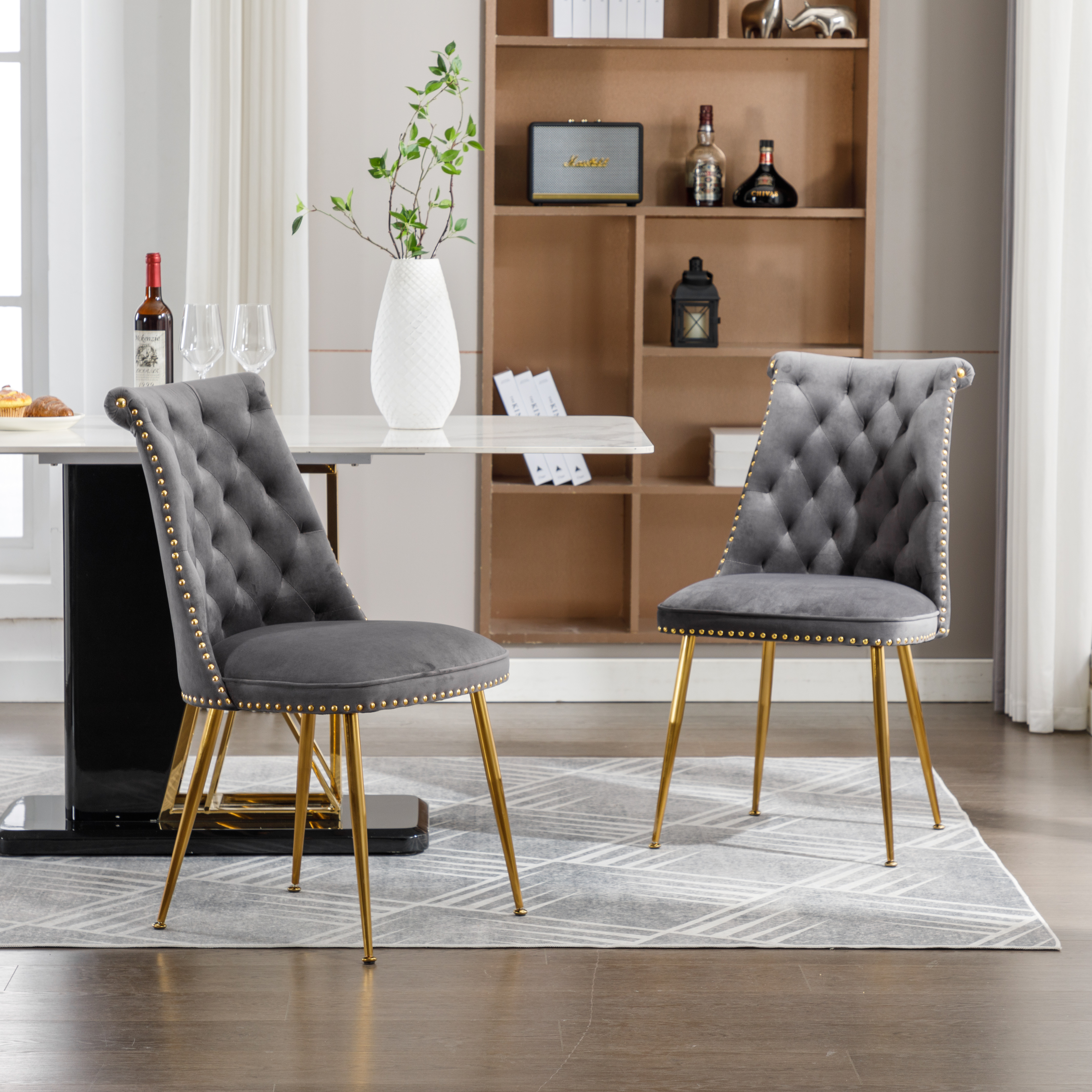 Zwei graue Samtstühle mit goldenen Beinen. Die Stühle stehen in einem Esszimmer.