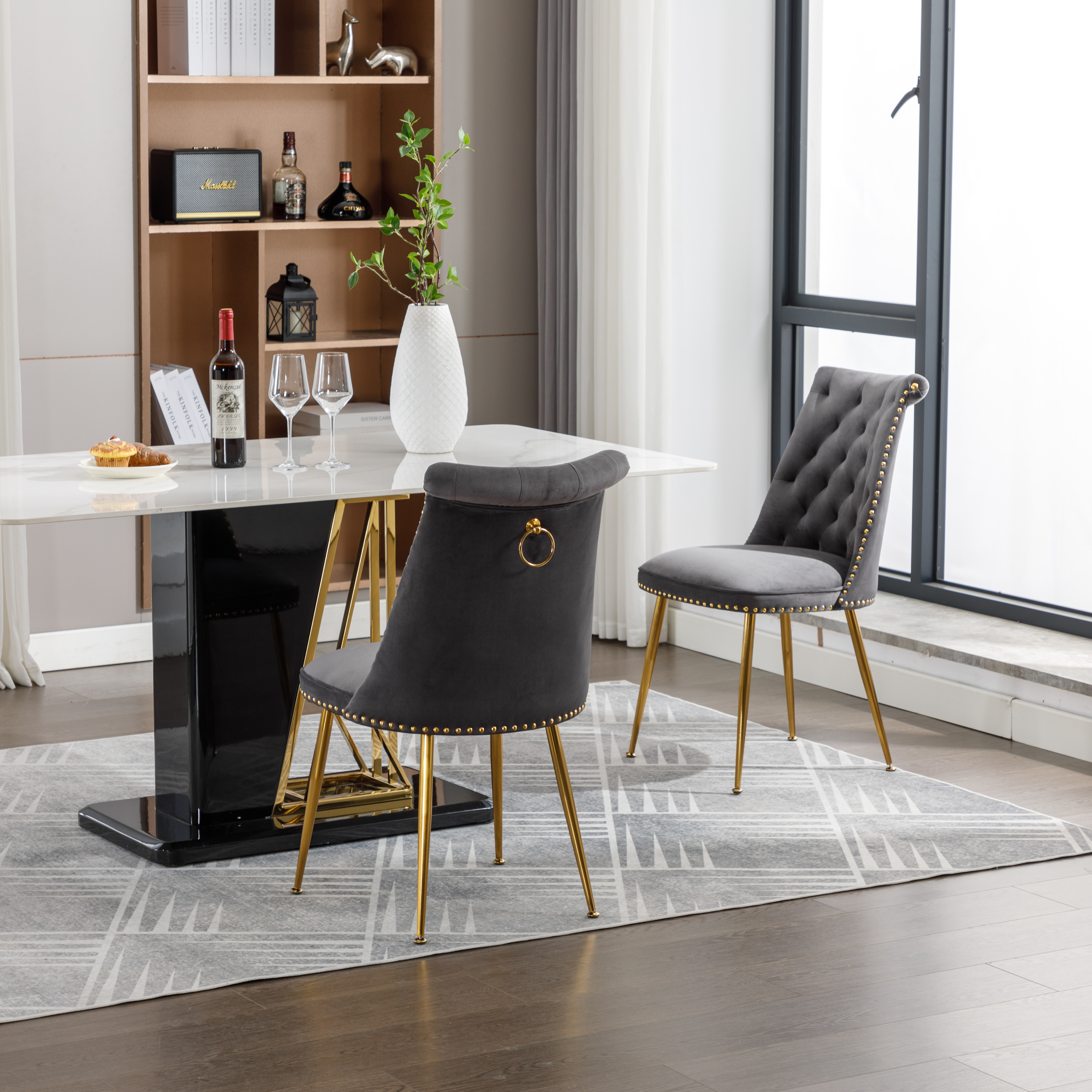 Zwei graue Samtstühle mit goldenen Beinen. Die Stühle stehen in einem Esszimmer.