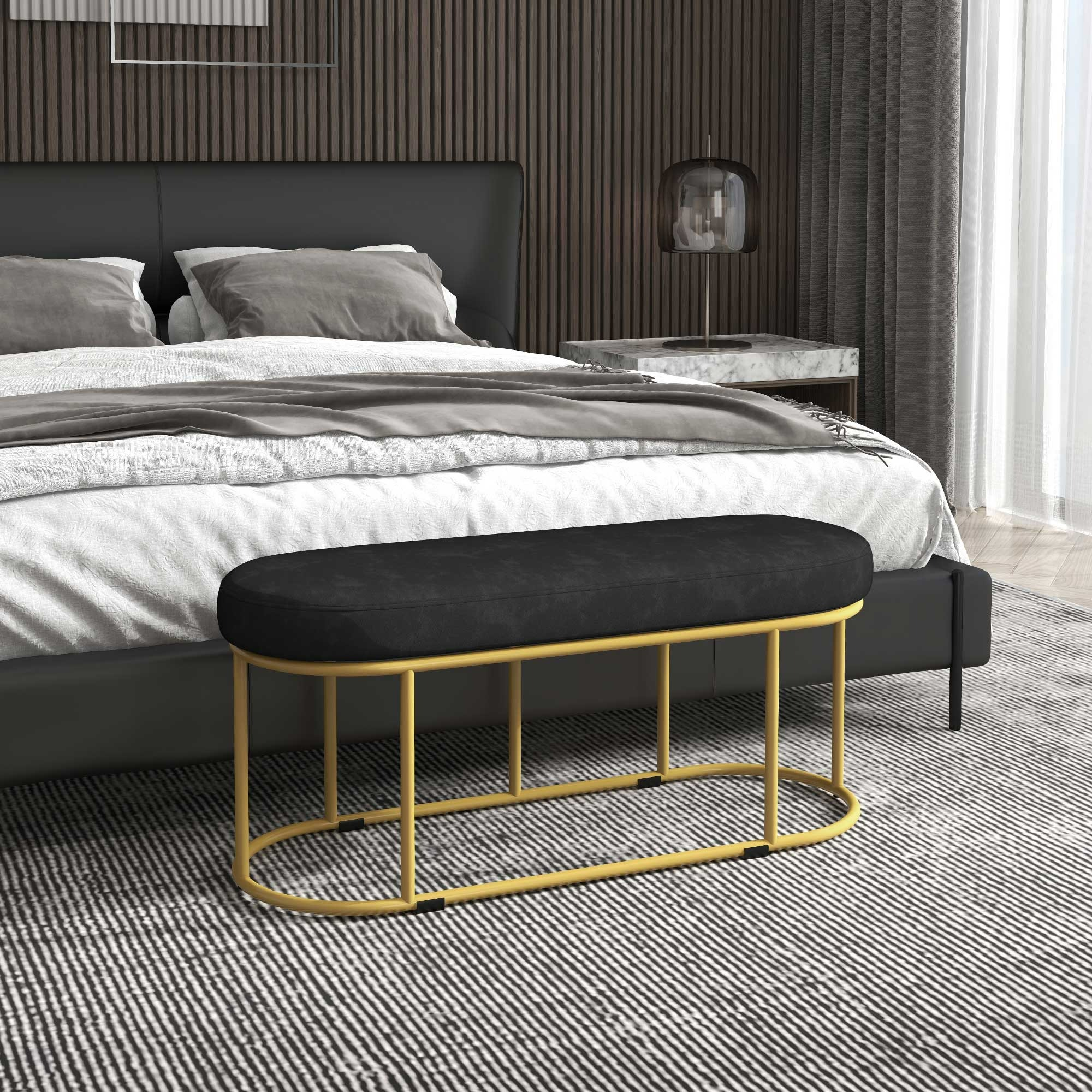 Schwarze Bank mit goldenen Beinen in einem Schlafzimmer. Bett im Hintergrund. Gestreifter Teppich.
