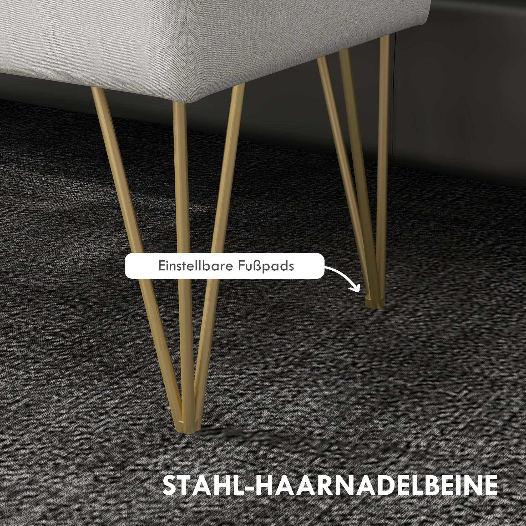 Eine weiß gepolsterte Bank mit goldenen Haarnadelbeinen steht auf einem gemusterten Teppich.