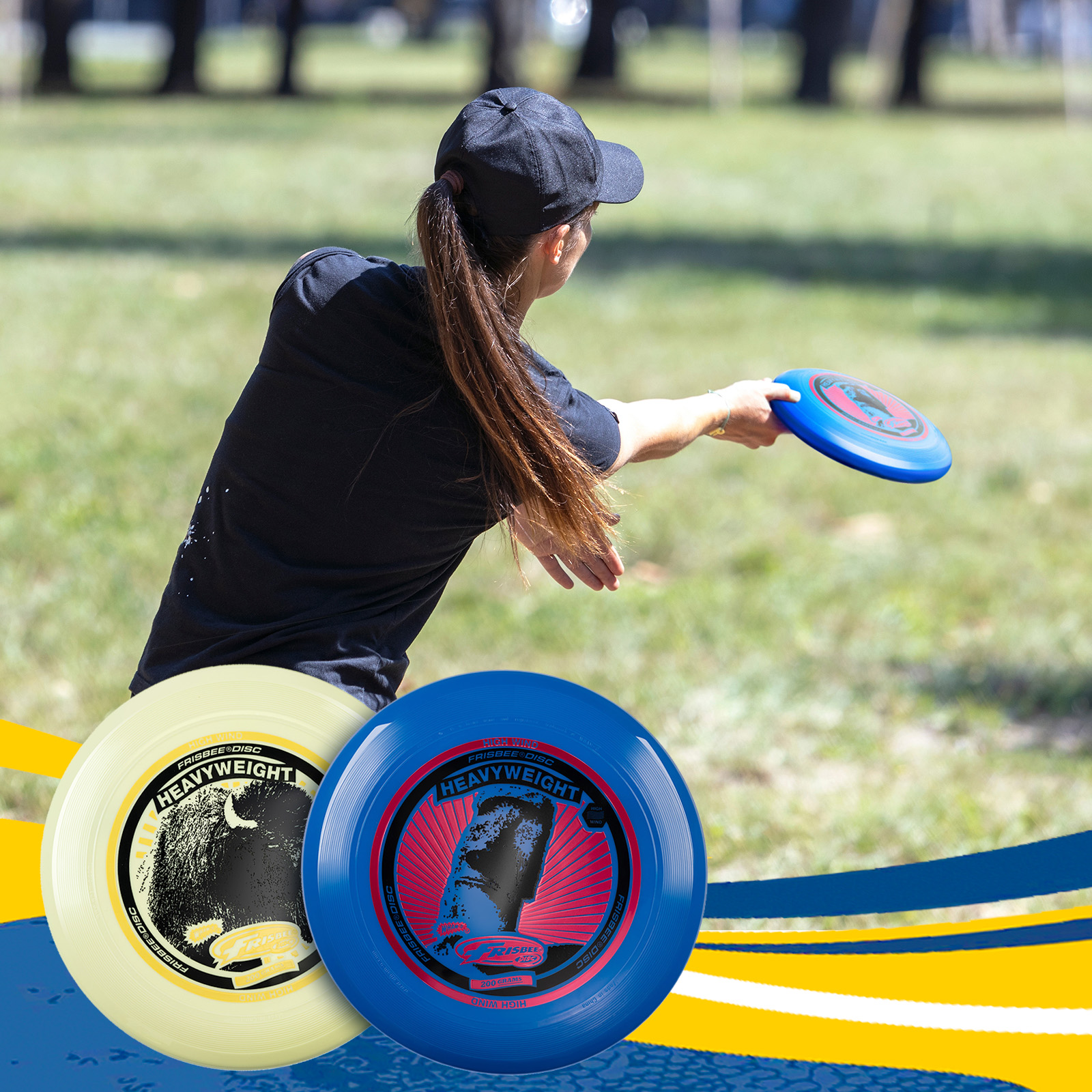 Frau wirft blaue Frisbee, zwei Frisbees im Vordergrund.