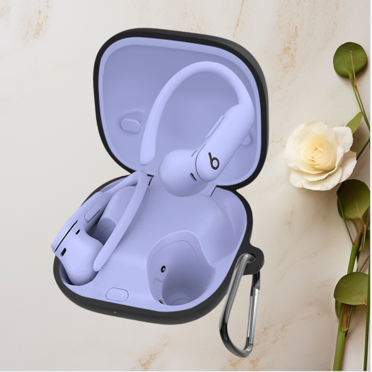 Beats-Kopfhörer in einem Etui. Die Kopfhörer sind lila und das Etui ist schwarz. Rechts ist eine weiße Blume.