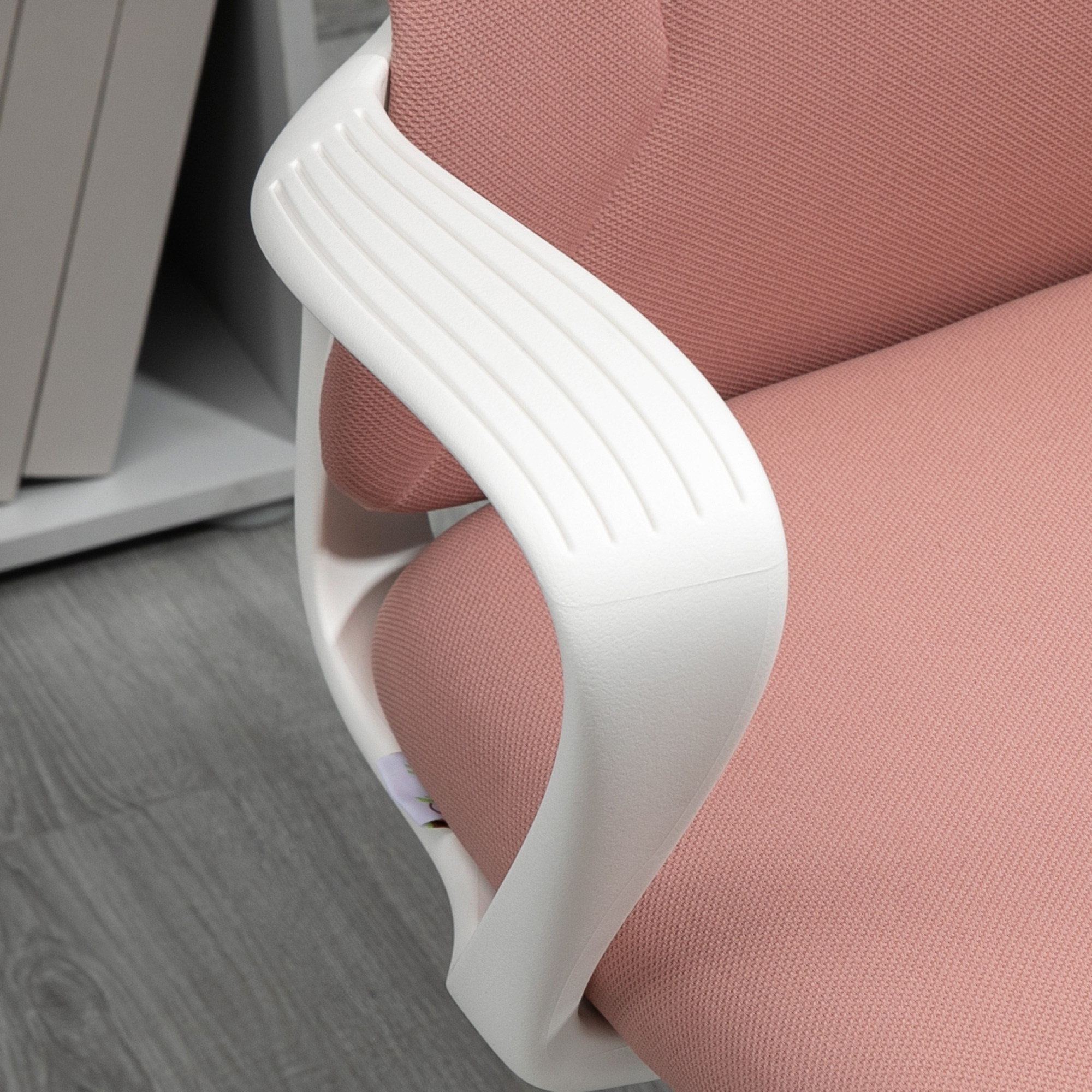 Primo piano del bracciolo di una sedia da ufficio rosa. Bracciolo bianco con design curvo.