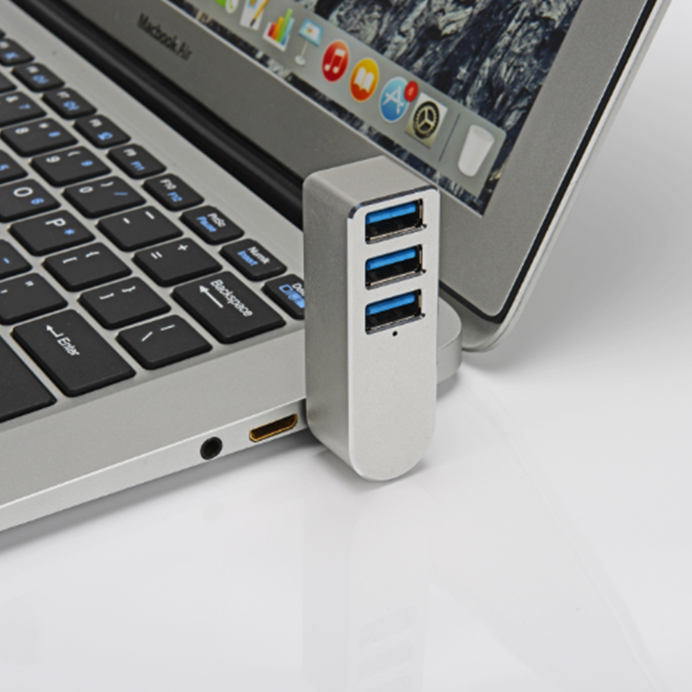 Ein silberner USB-Hub, der mit einem Laptop verbunden ist. Drei blaue USB-Anschlüsse sind sichtbar.