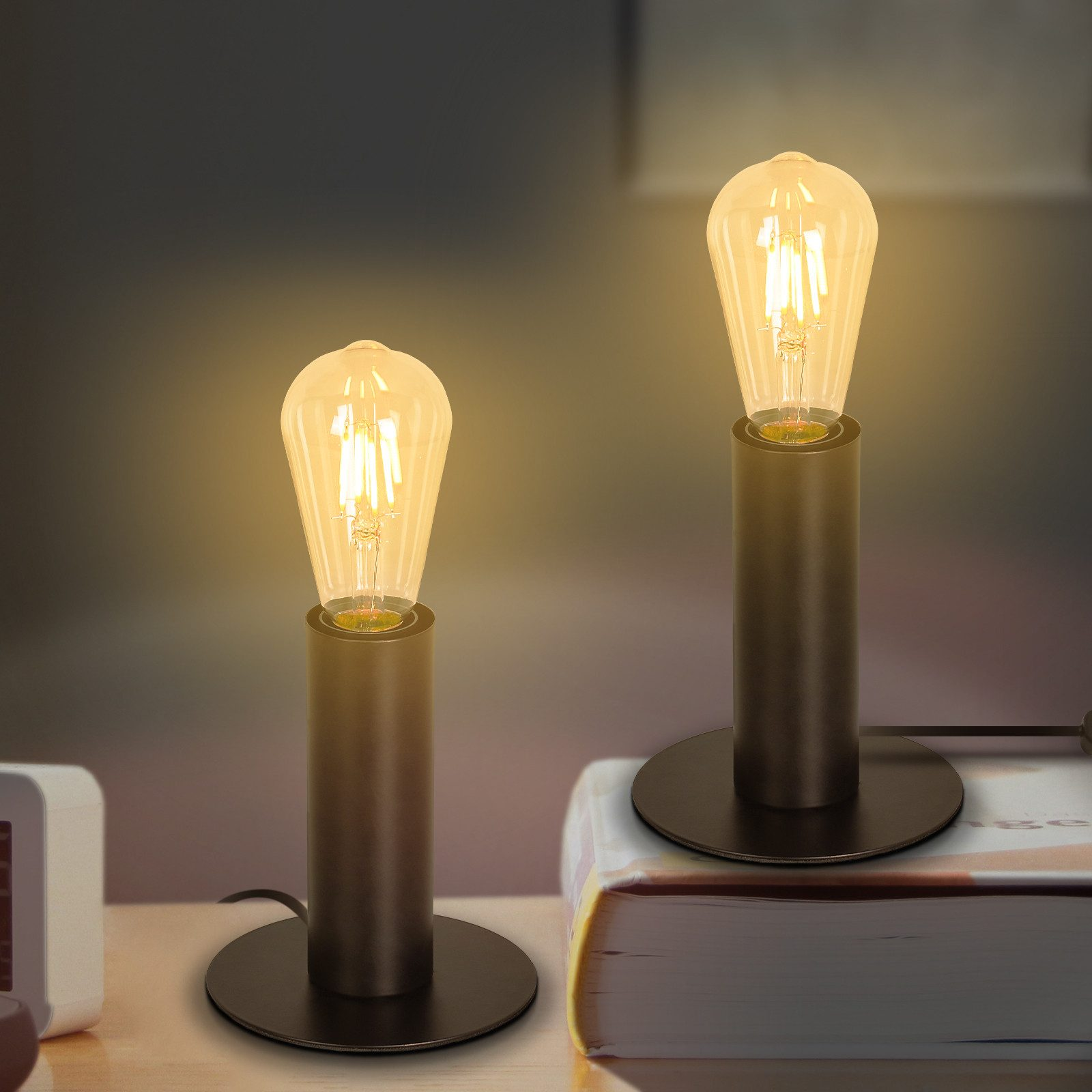 Dwie lampy z czarnymi podstawami i żarówkami w stylu vintage na ciemnym tle.