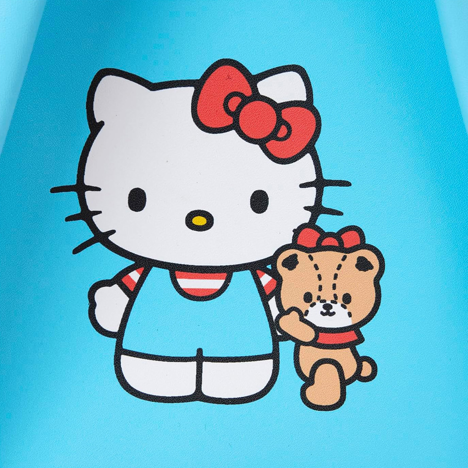 Hello Kitty y un osito de peluche sobre fondo azul. El oso sostiene un lazo rojo.