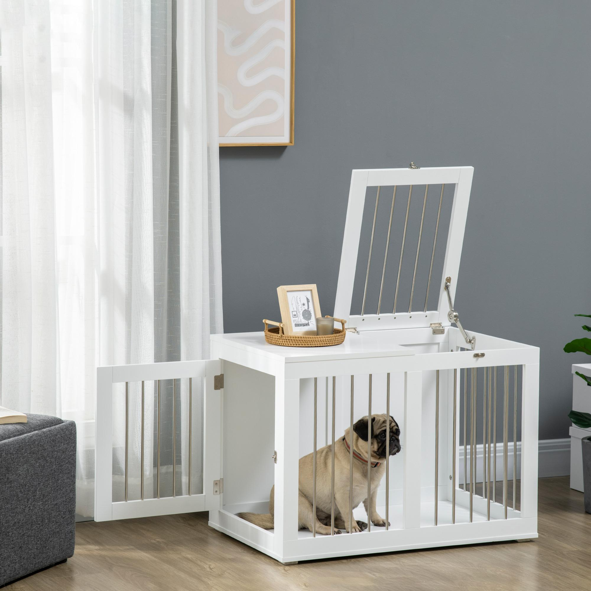 Eine weiße Hundebox mit einem Mops darin, offene Tür. Ein Bild und Deko im Hintergrund.